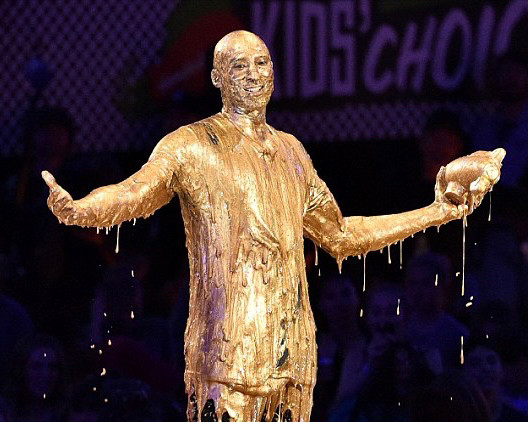 A smiling guy (Kobe Bryant) covered in liquid gold.