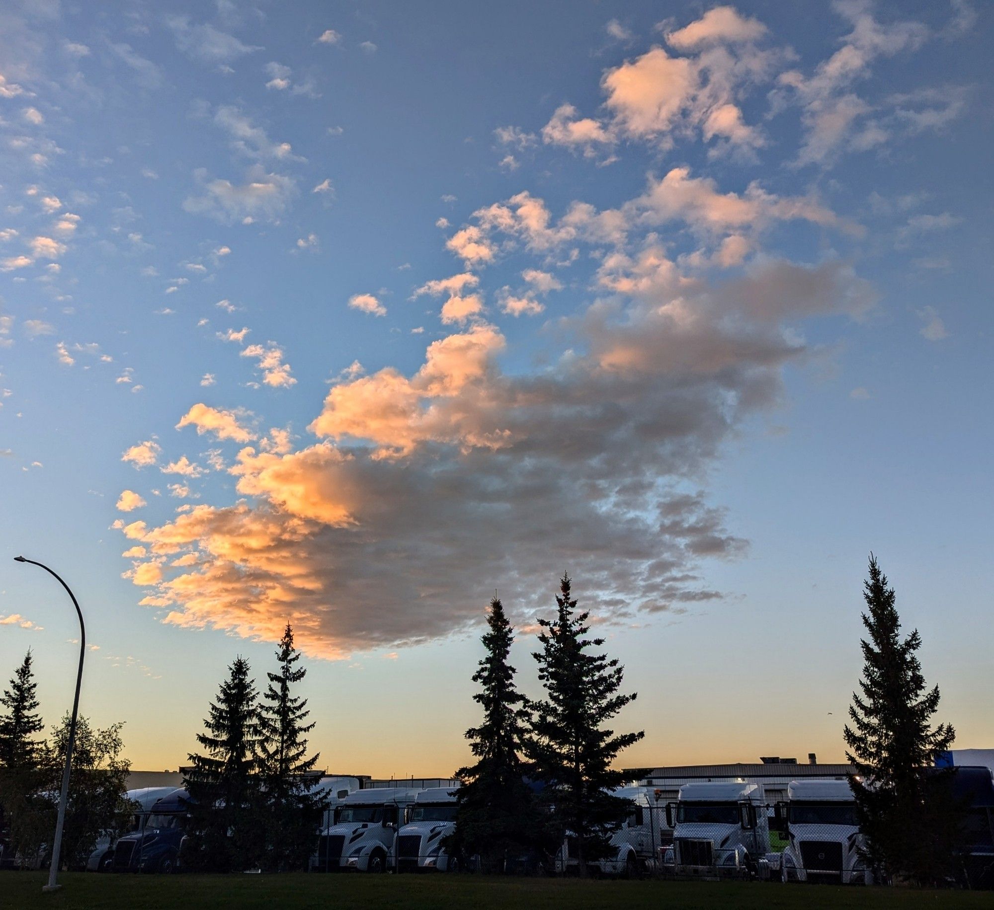 Picture of a cloud with the light from the sunrise giving it orange highlights. The colours look a little like a painting by impressionist artist, Monet.