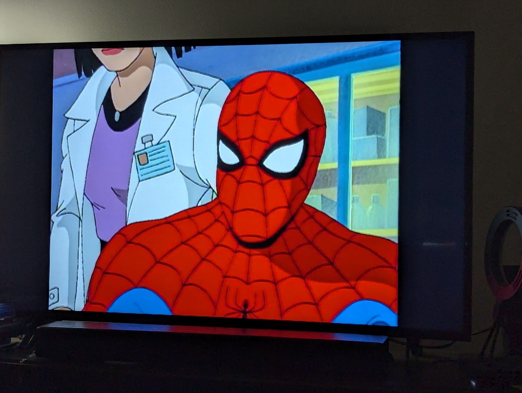 Scene from the Spider-Man animated series featuring the titular character sitting at a desk with a scientist standing behind him.