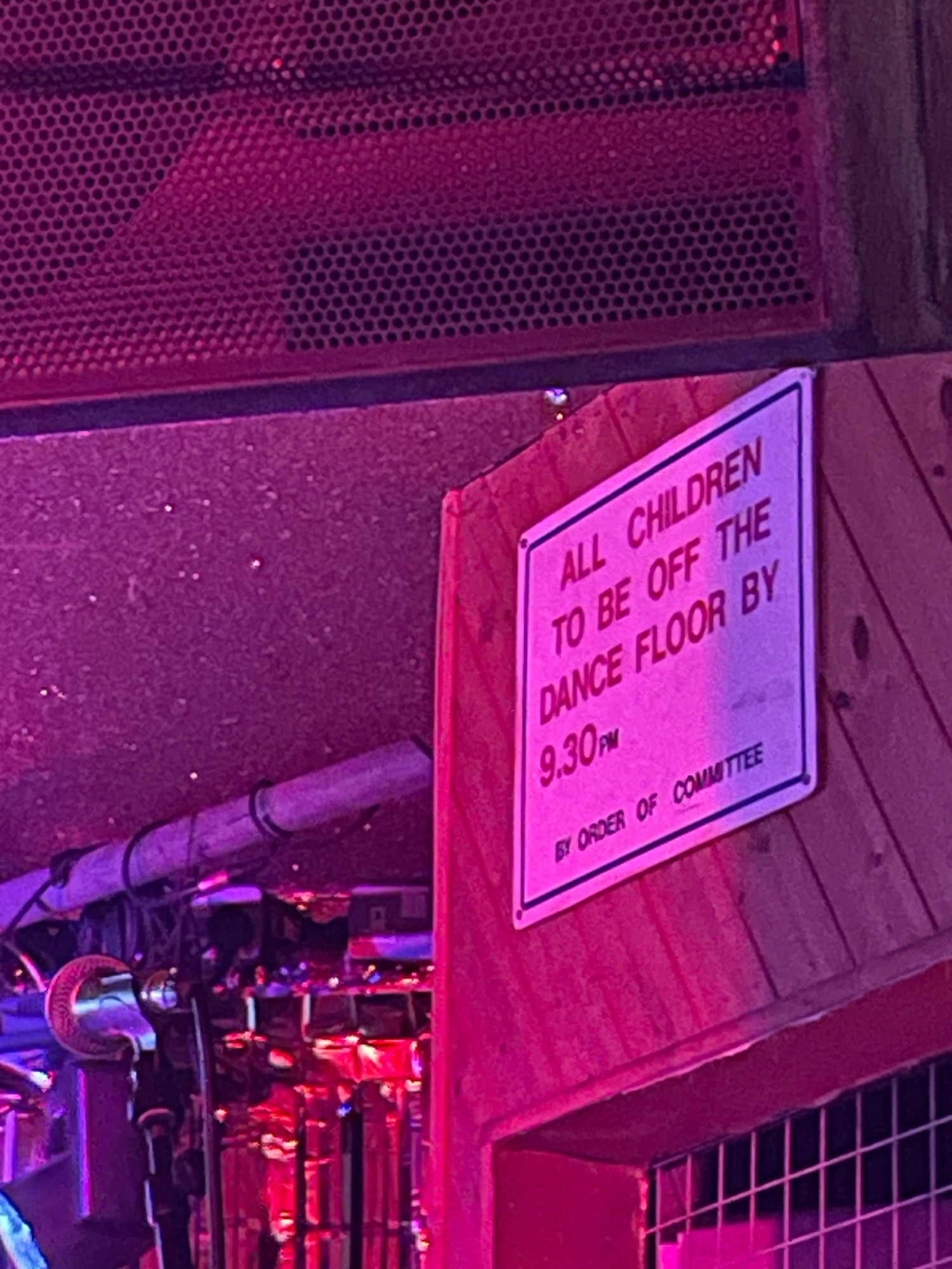 A sign on the wall of an entertainment venue reading “All children to be off the dance floor by 9.30pm by order of committee”