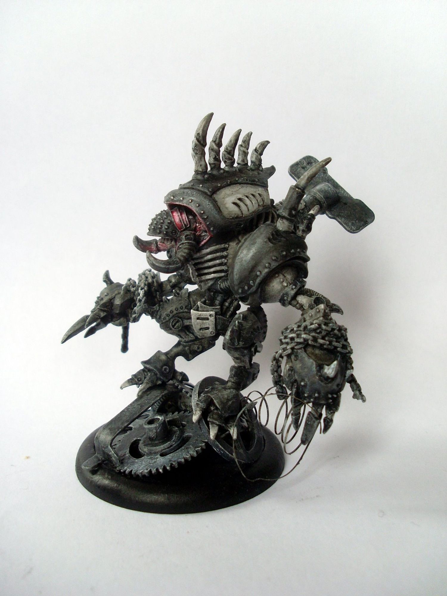 Miniature of a Warmachine Cryx Warjack steampunk robot dude whose exact name I forgot.  Has claws and chains and spikes everywhere, real edegelord energy. Painted in monochrome dirty grey except for some red light effects around the head.