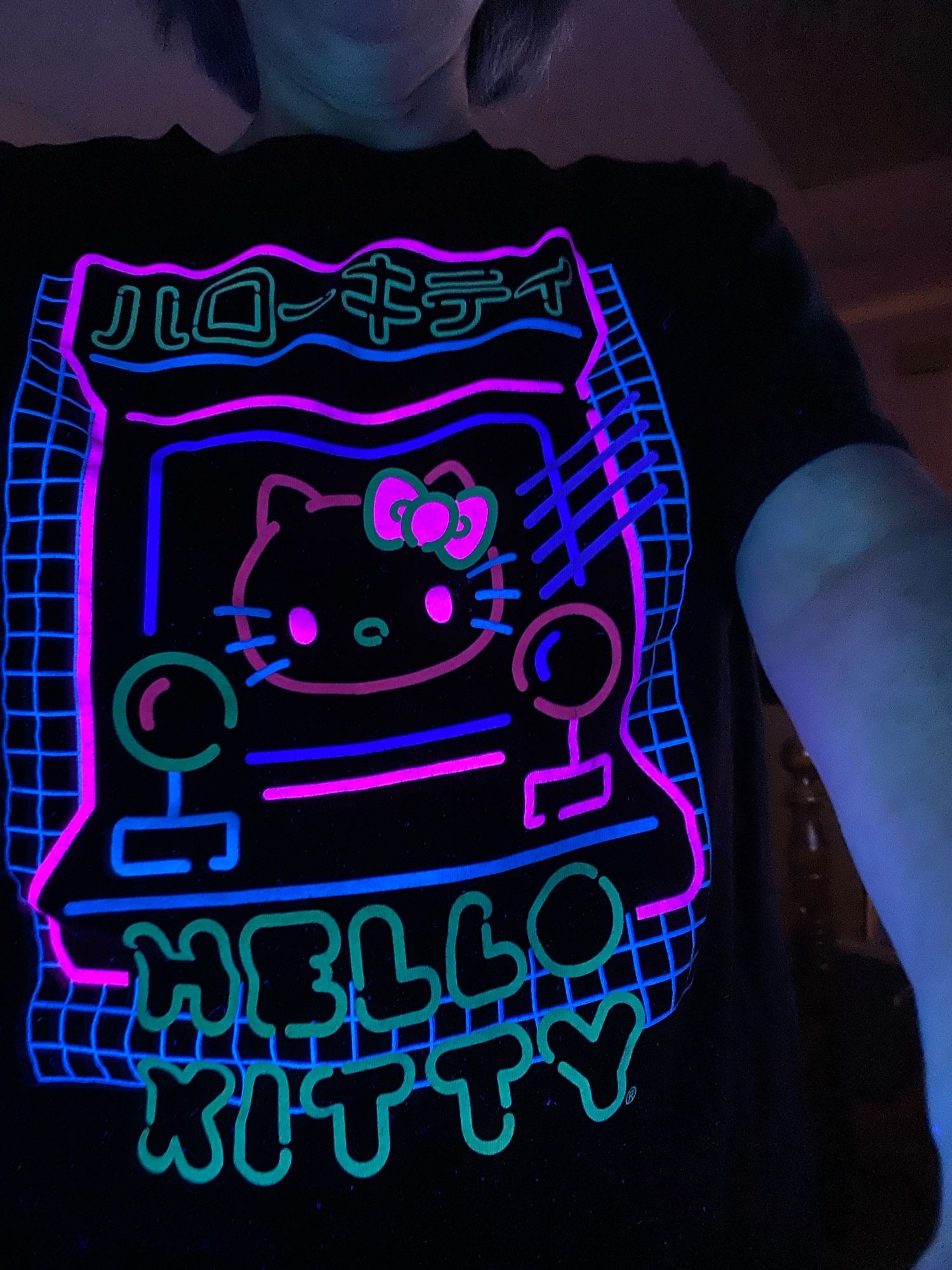 Hello kitty t shirt with neon colors on black background. Black light is on making colors pop!