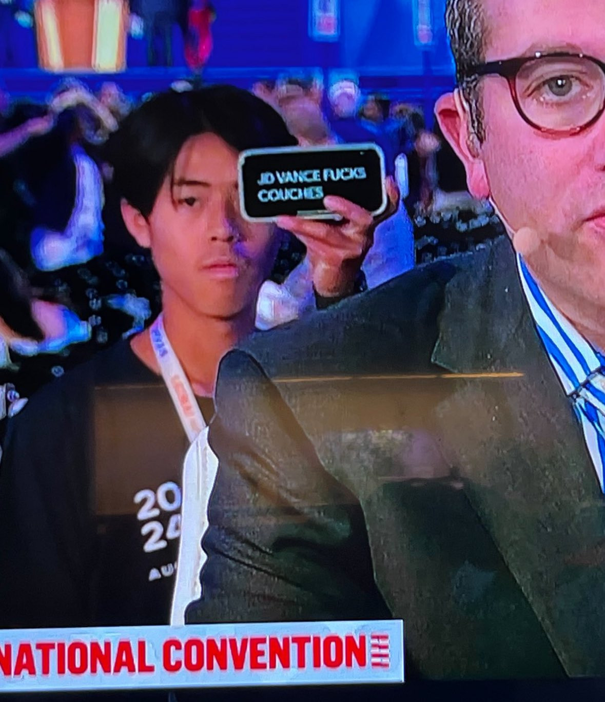 MSNBC screenshot with a young person in the background holding a phone with a message of truth: "JD VANCE FUCKS COUCHES"