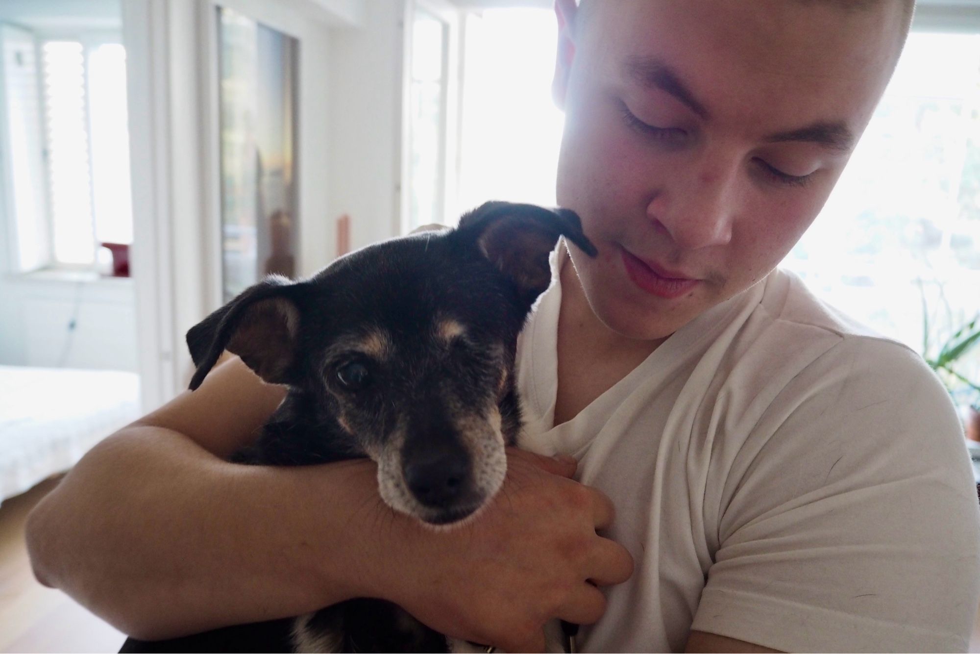 Young man holding dog.