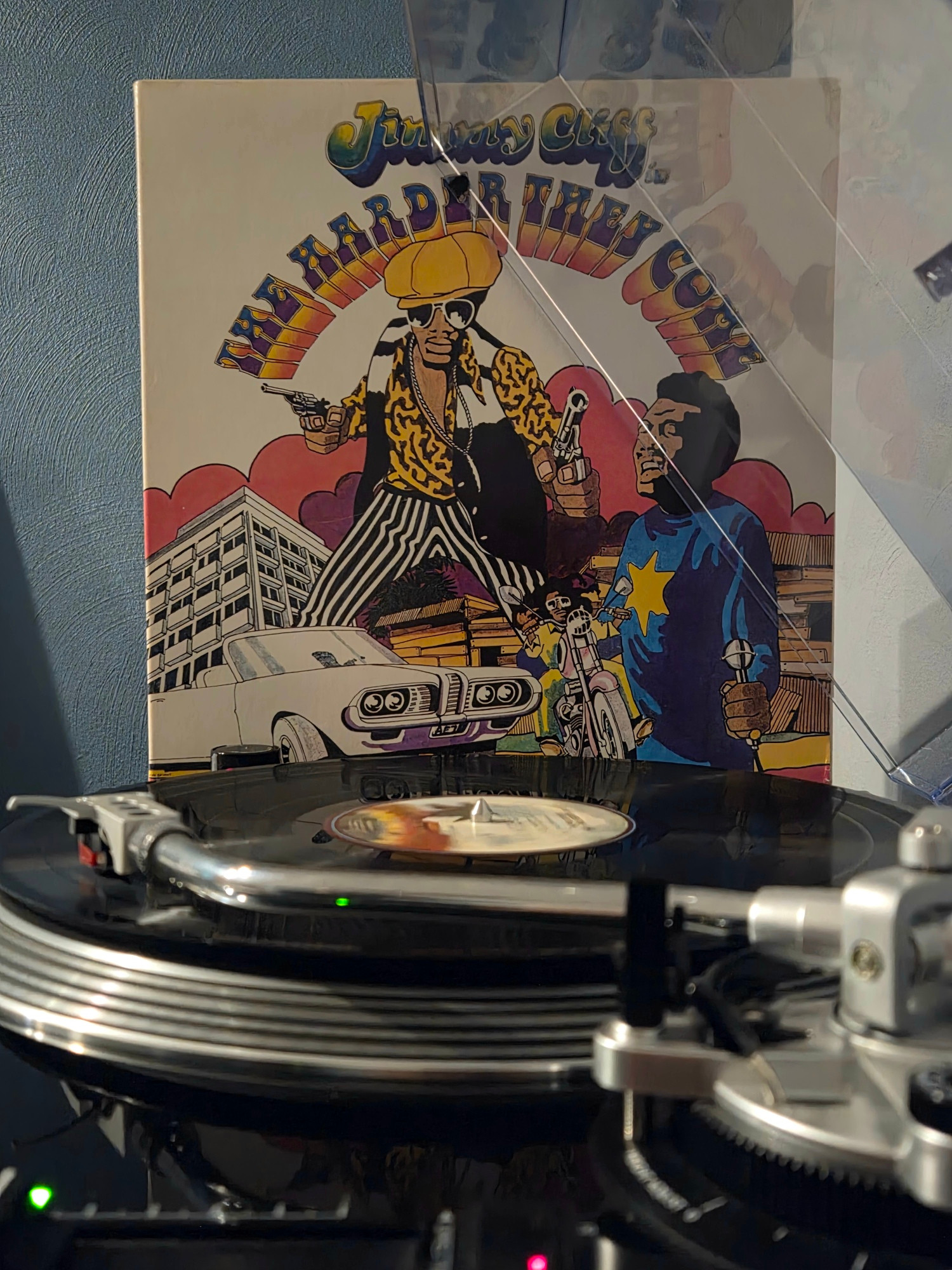 Side view of a black AT-LP120 spinning The Harder They Come motion picture soundtrack, its gatefold jacket propped up against the dust cover in the background