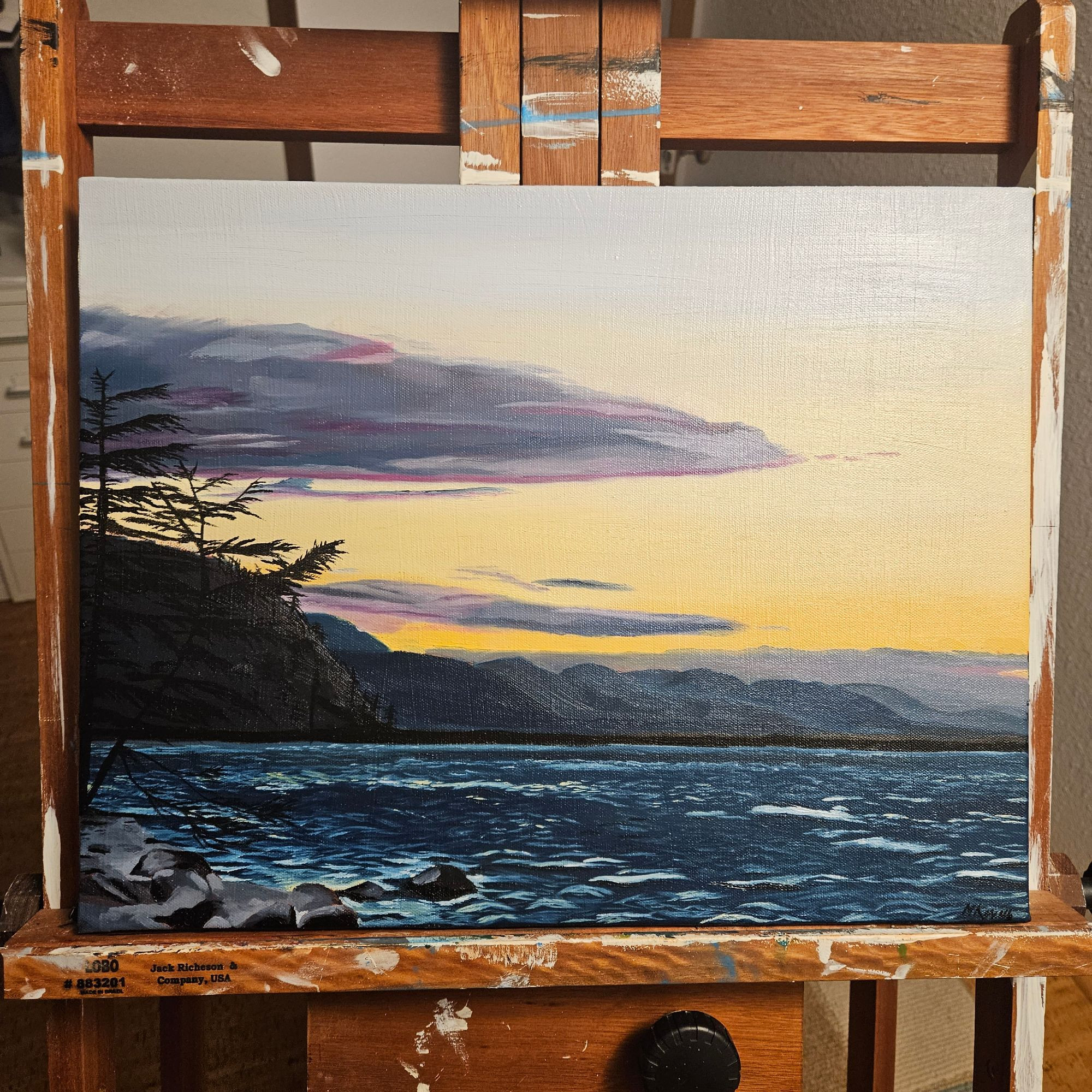 a 14x18 oil painting on canvas of Dungeness Spit in the Straight of Juan De Fuca at sunset with lots of purple and pink tinged clouds and calm seas. The view is towards Port Angeles. 