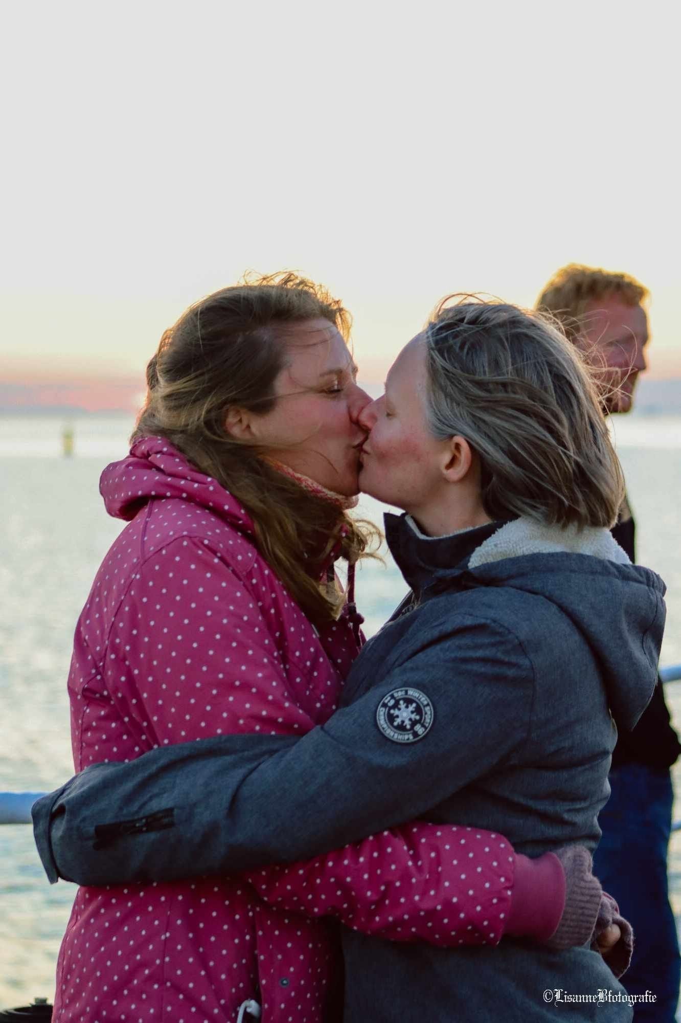 Twee heel koude lesbische vrouwen die elkaar innig omhelzen en kussen bij zonsondergang