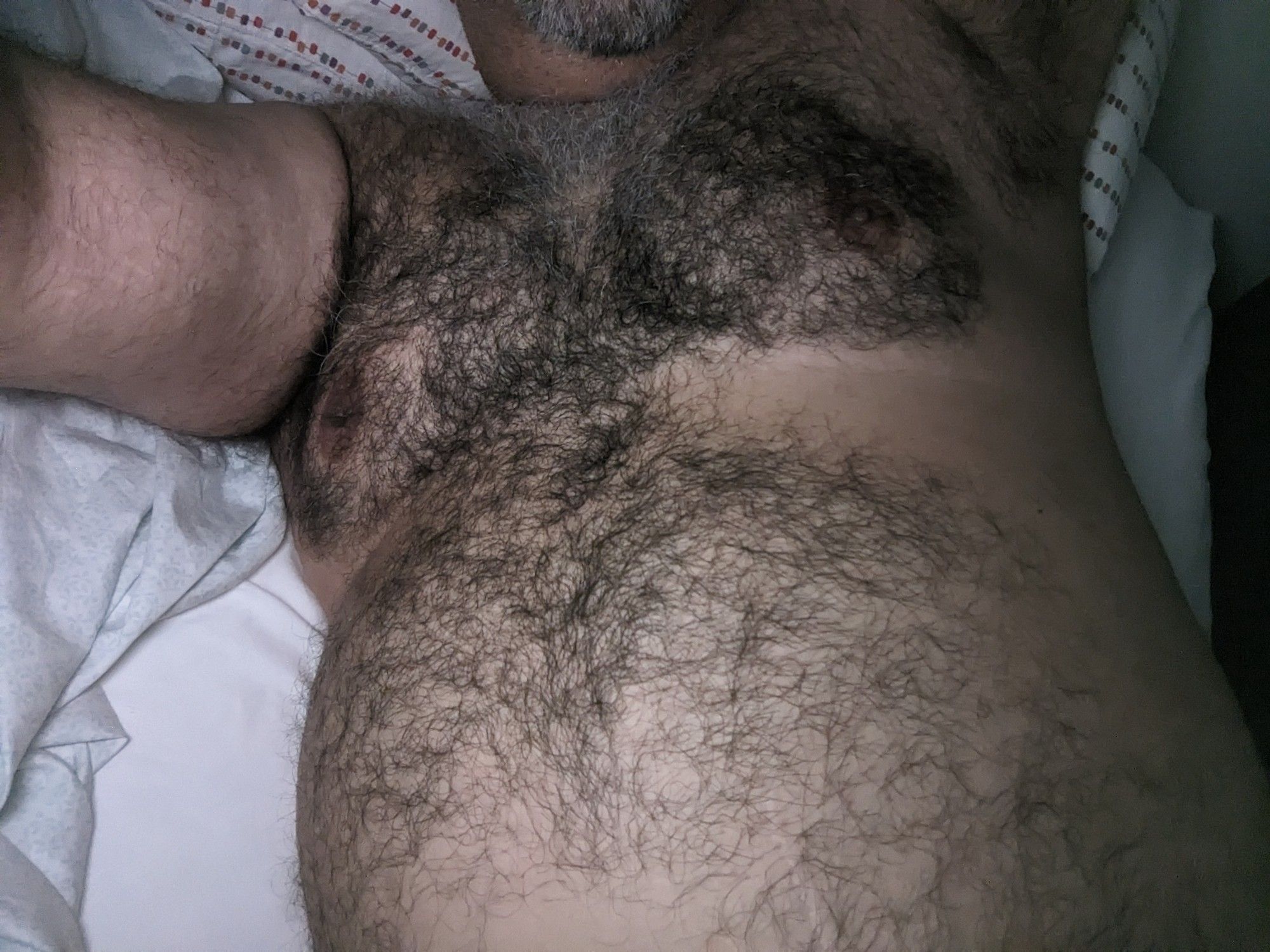 Selfie pic of moi wearing in bed, shirtless, showing off my tummy.