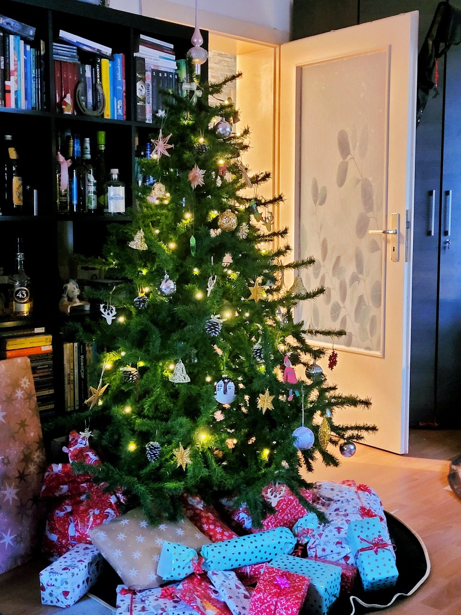 Ein geschmückter Weihnachtsbaum, unter dem eingepackte Geschenke liegen.