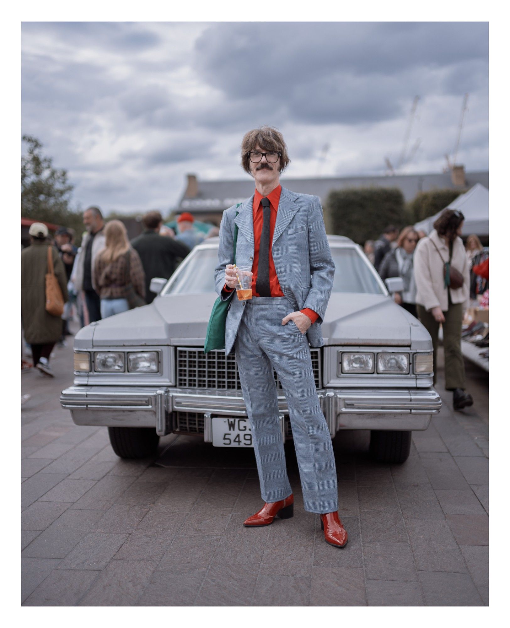 Portrait of a man in vintage clothing in front of a classic car.