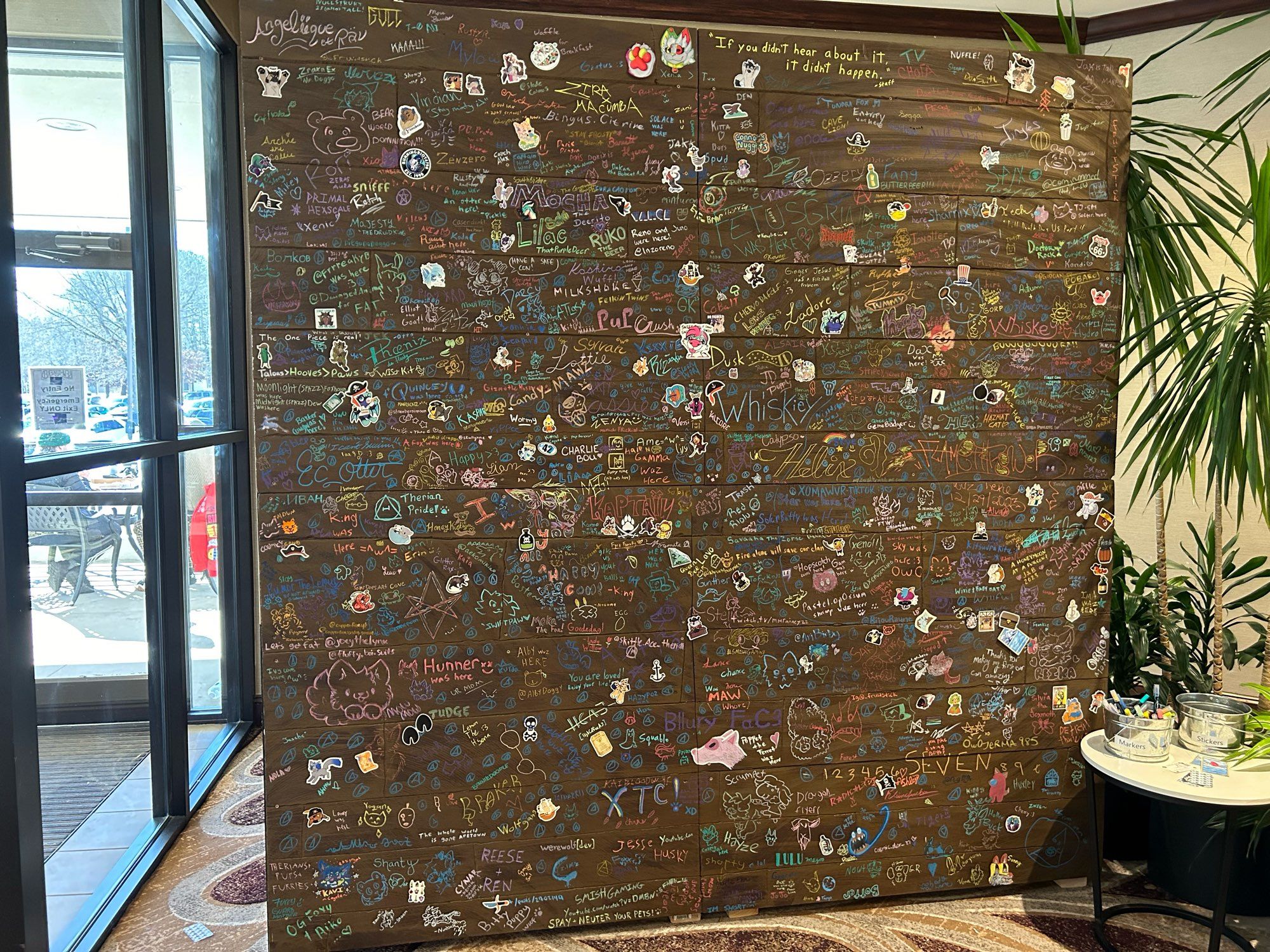 A wall at a furry convention upon which many people contributed their drawings, words, and stickers.