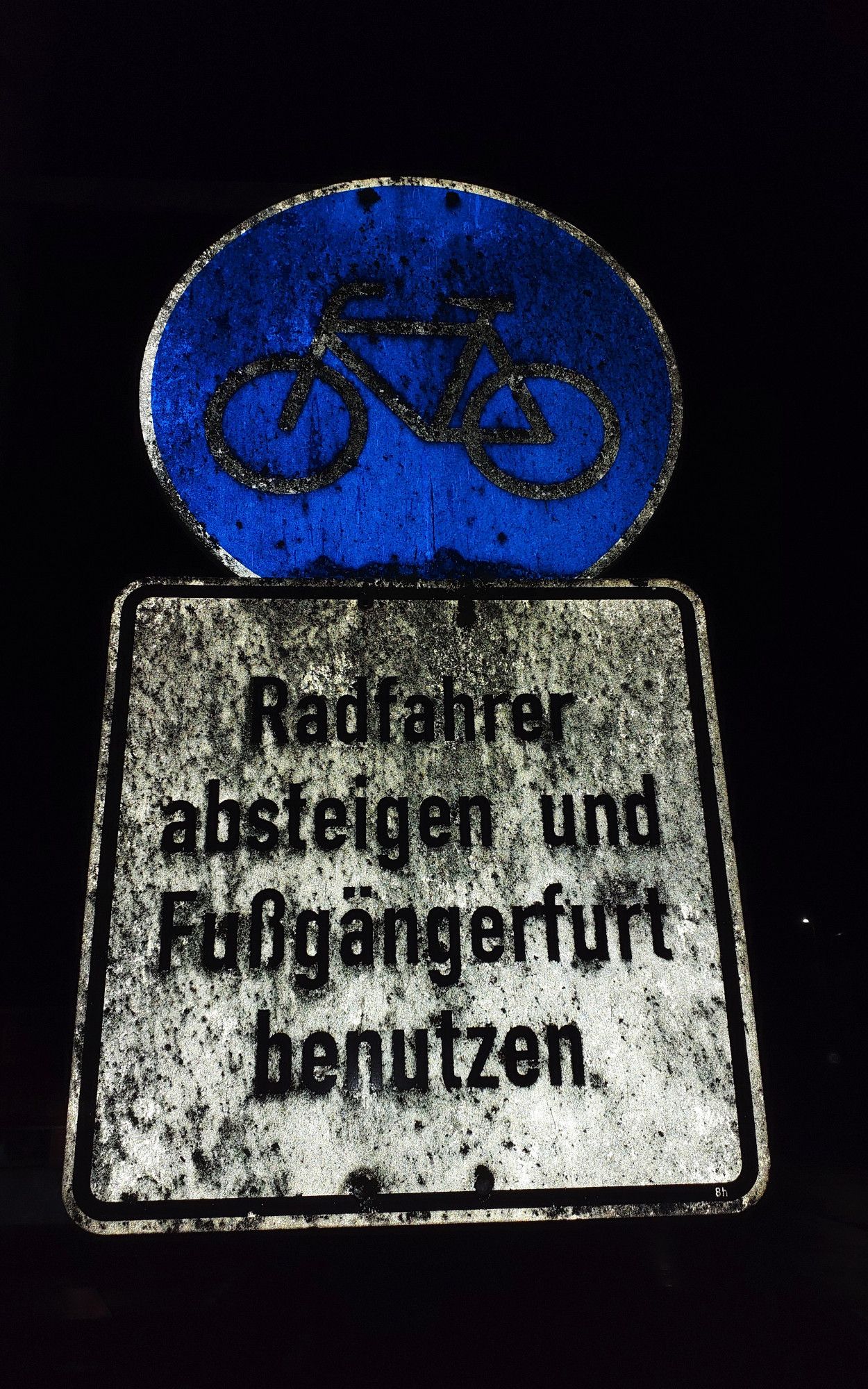 VZ 237 (Radweg) mit Zusatzzeichen darunter. Auf dem Zusatzzeichen steht: Radfahrer absteigen und Fußgängerfurt benutzen.