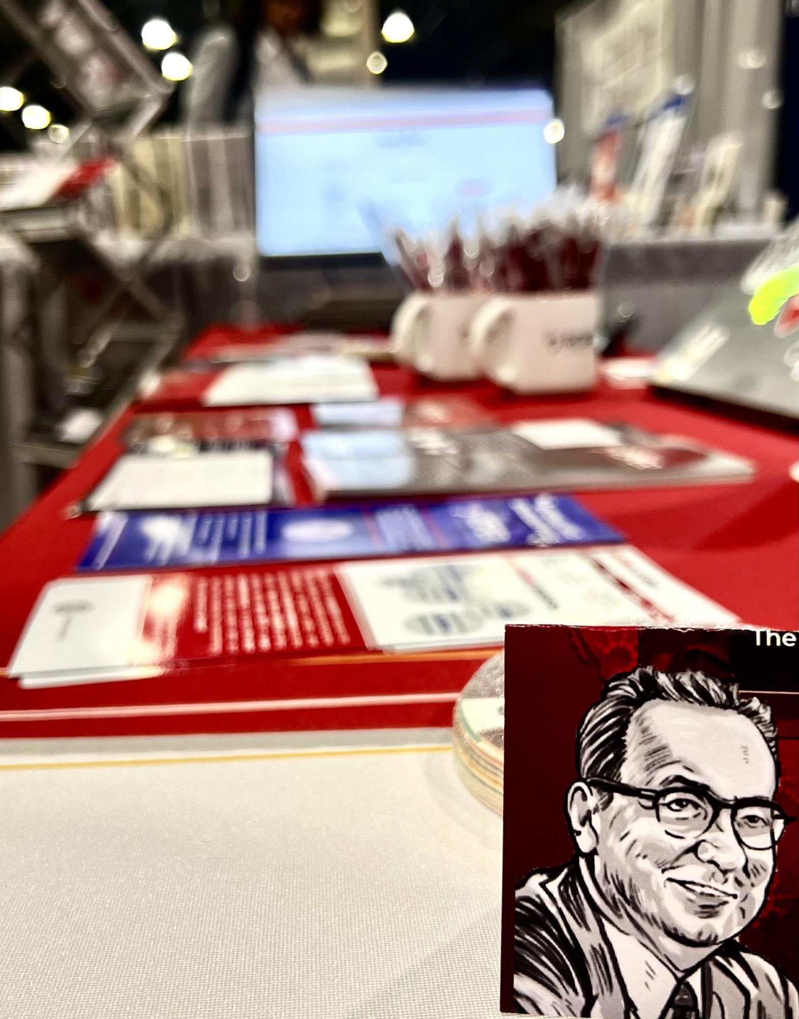 Photo of exhibit hall table with cartoon image of Elmo Roper in bottom right corner