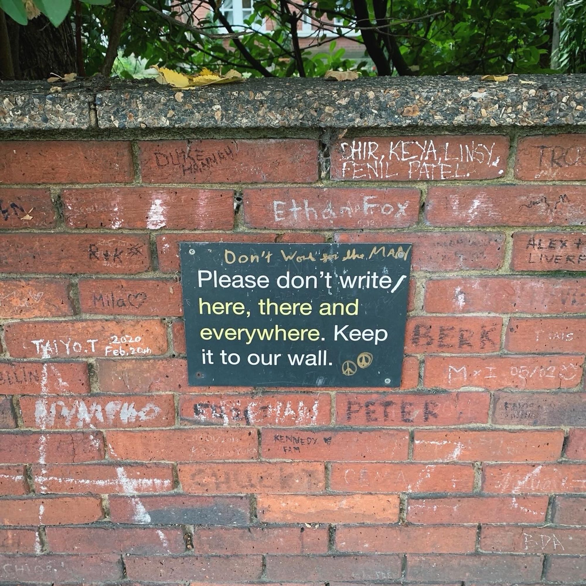 A sign on the wall next to Abbey Road Studios, meant to prevent graffiti on the neighbors property, that says: “Please don't write/ here, there and everywhere. Keep it to our wall.”