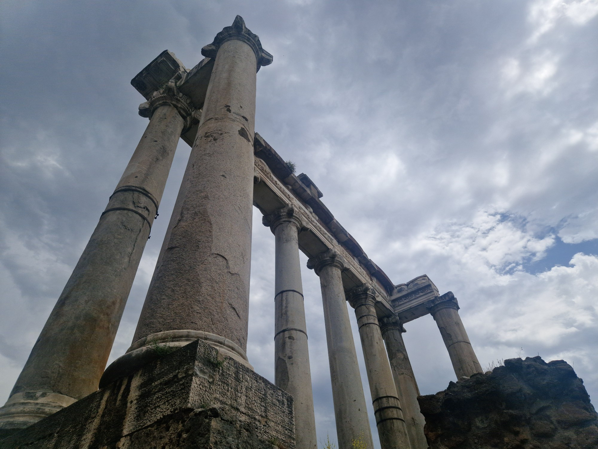 Temple of Saturn viewed from below, huge colums set against a cloudy sky