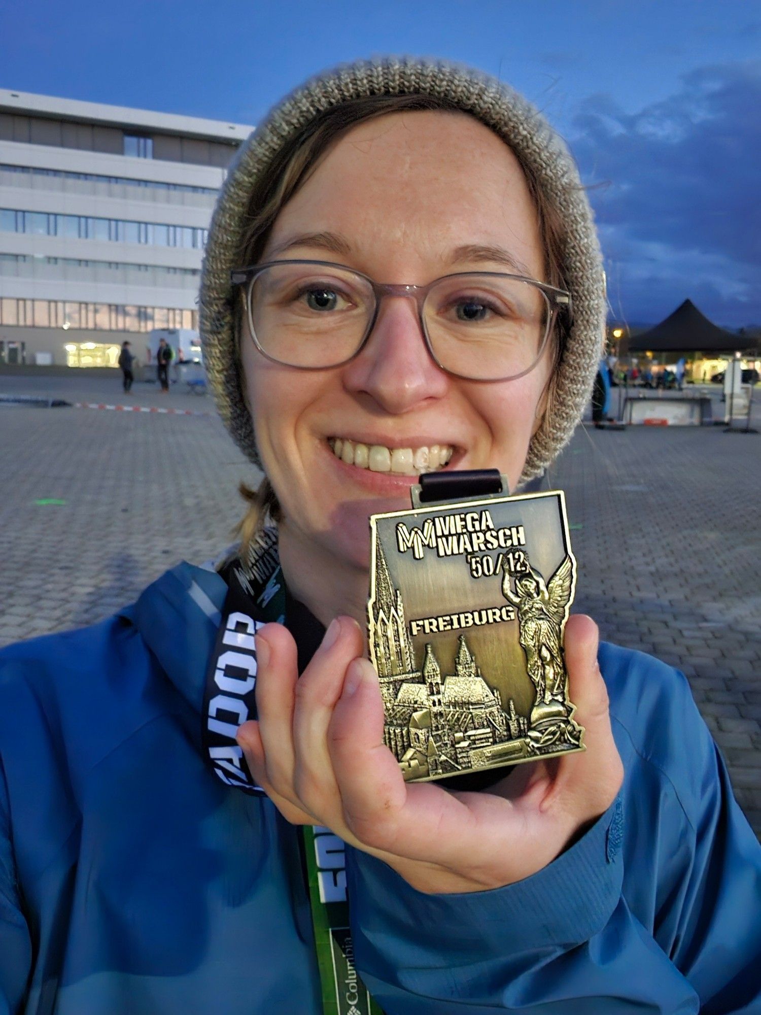 Ich in Regenjacke und Wollmütze, halte meine Lokalmatadormedaille in die Kamera.