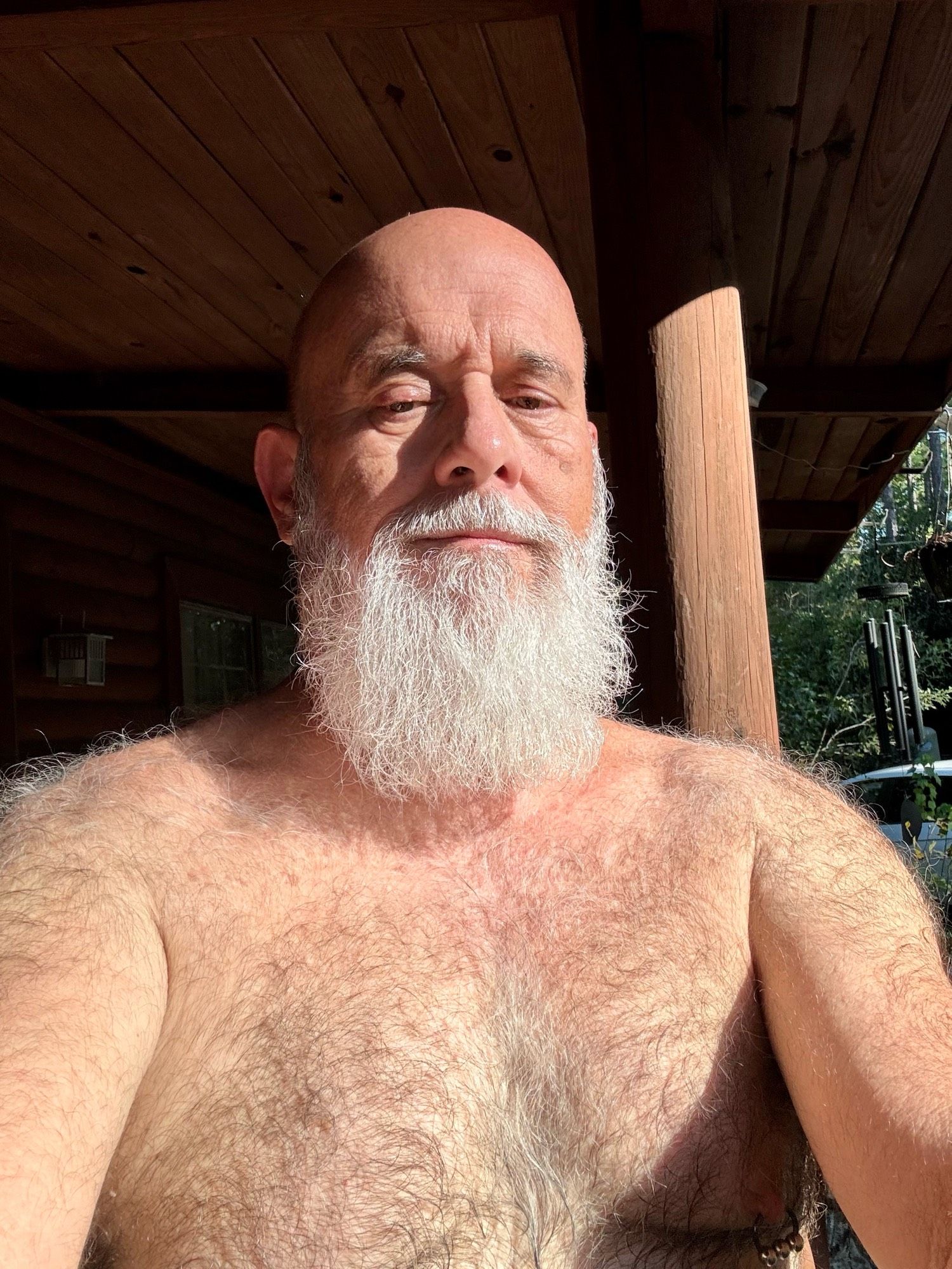 Shirtless man with a white beard, facing the camera, lit by sunshine. NO GENITALIA SHOWING.