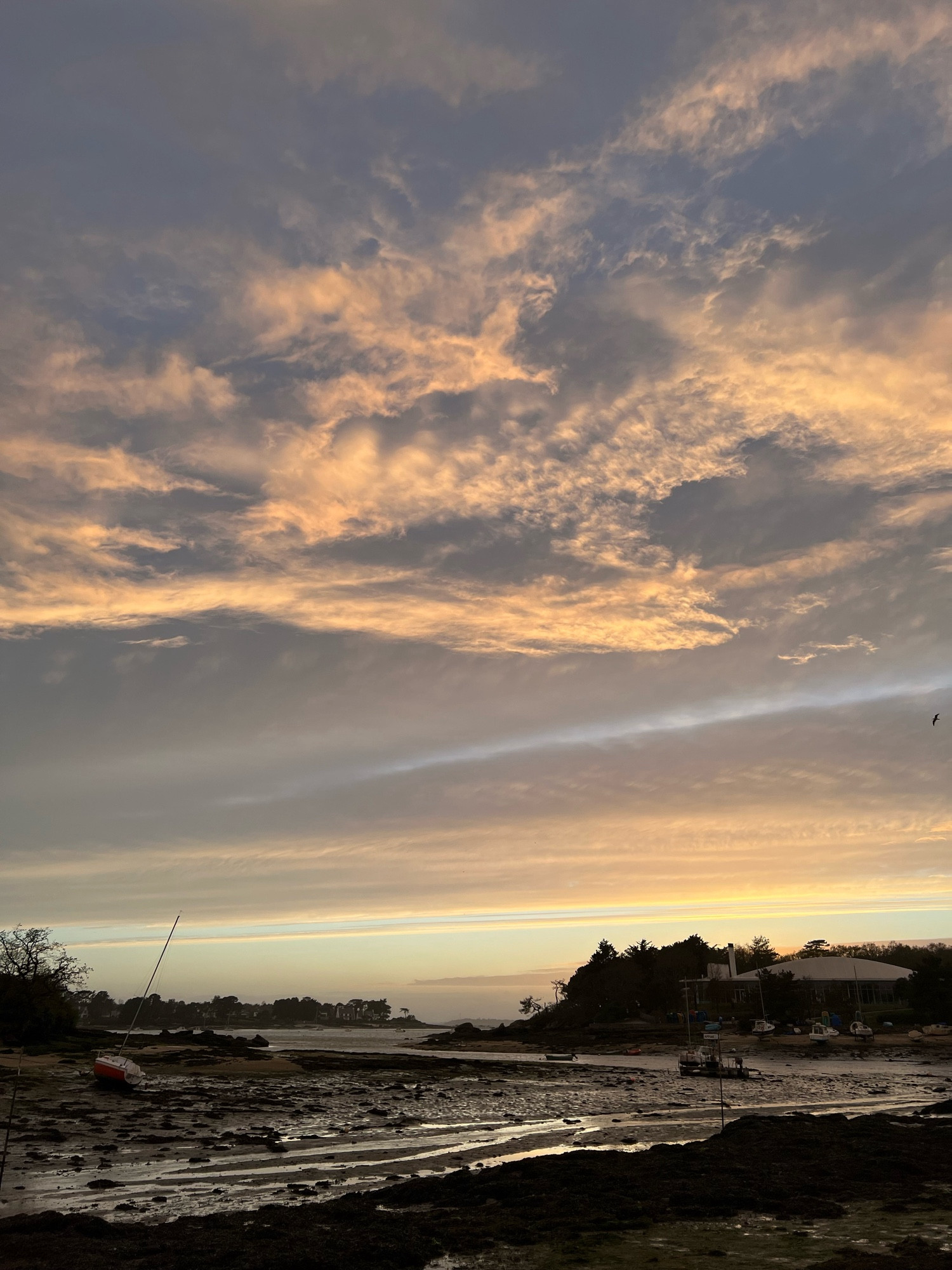 Vue sur la ria à marée basse peu après le coucher du soleil, les nuages sont dorés