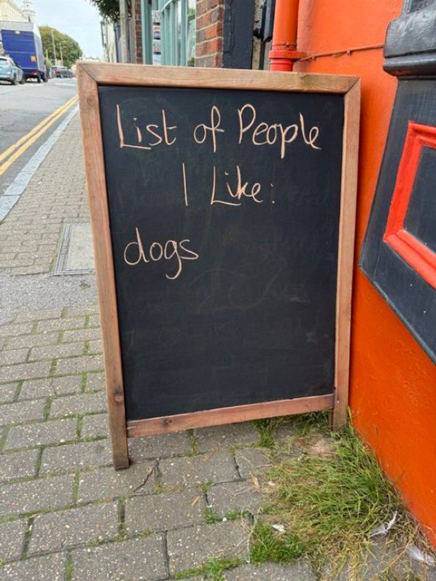 Tafel auf dem Gehweg mit handschriftlichem Text:
List of people I like: dogs 