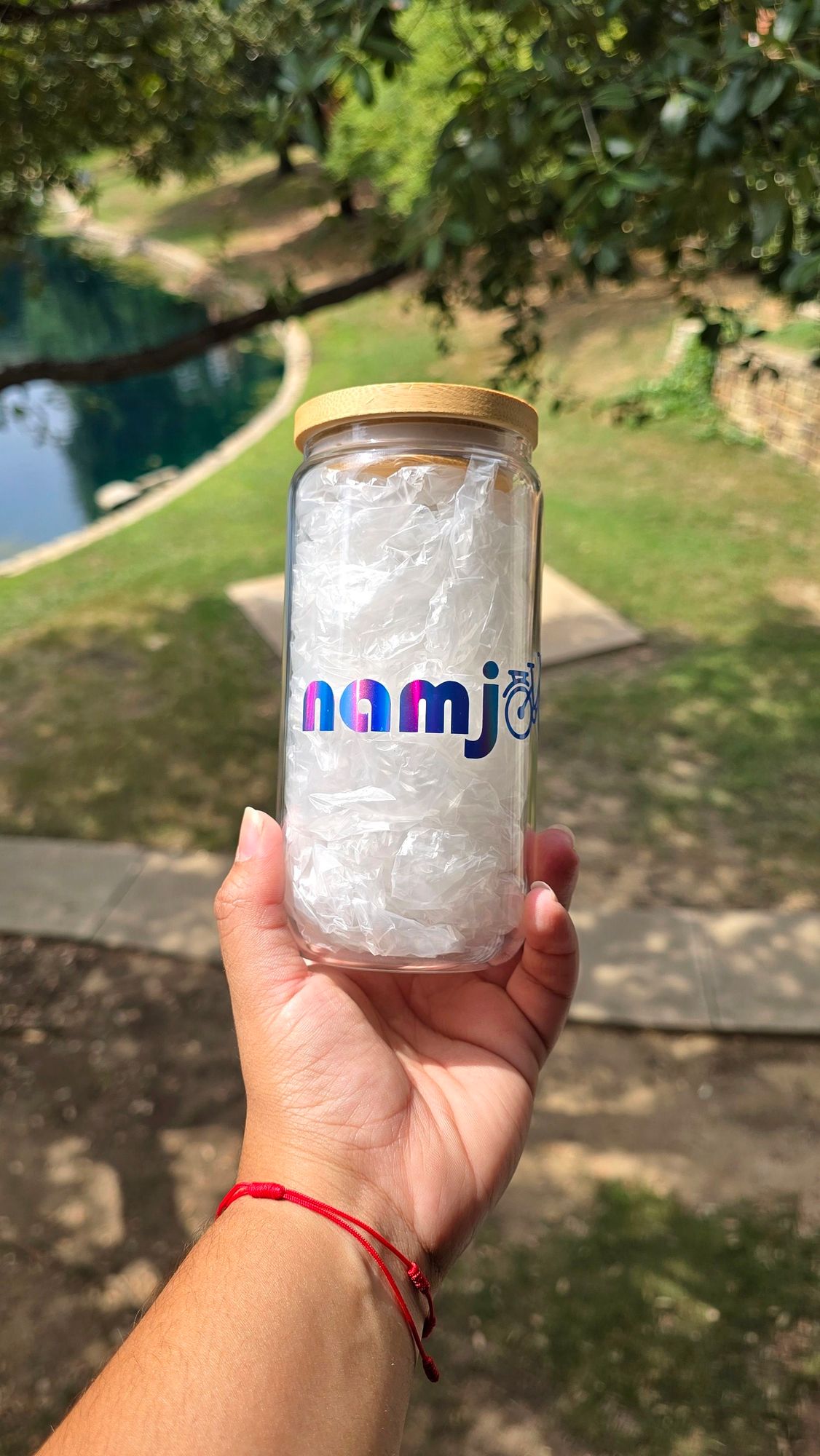 Can-shaped glass cup with the word 'Namjooning' on in holographic blue permanent vinyl. The double 'o' in the word was replaced with a little bycicle