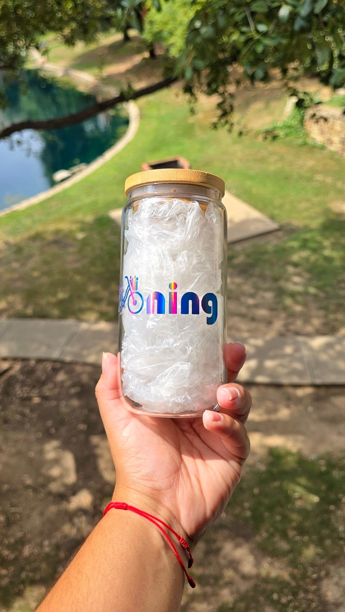 Can-shaped glass cup with the word 'Namjooning' on in holographic blue permanent vinyl. The double 'o' in the word was replaced with a little bycicle