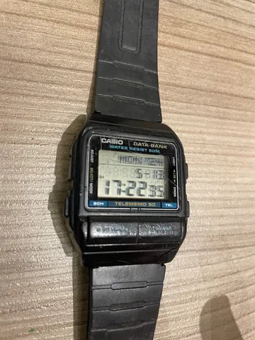 Um relógio digital Casio com muitos botões. O display é grande e pode mostrar palavras, além de data e hora. As inscrições "data bank" e "telememo" dão a entender que dá pra salvar telefones no relógio.