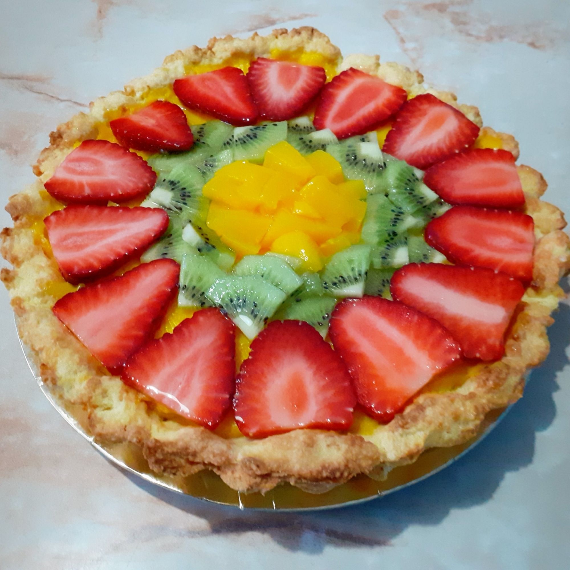 Custard tart topped with strawberries, kiwi and peach.