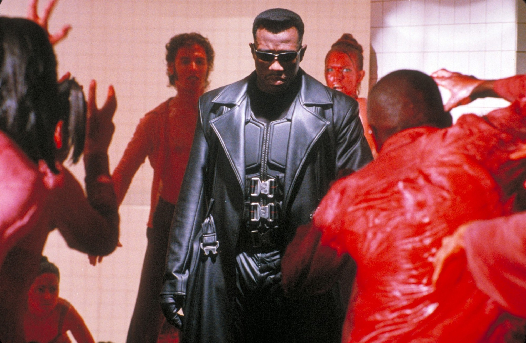 still from Blade (1998) wesley snipes as the titular blade center frame in body armor surrounded by blood soaked vampires. he is calm like a statue