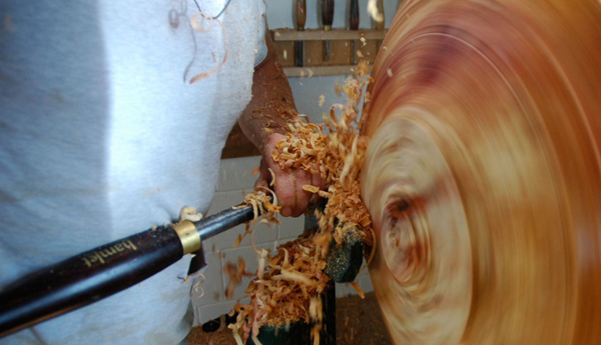 still of huge treetrunk in woodturning lathe being carved down