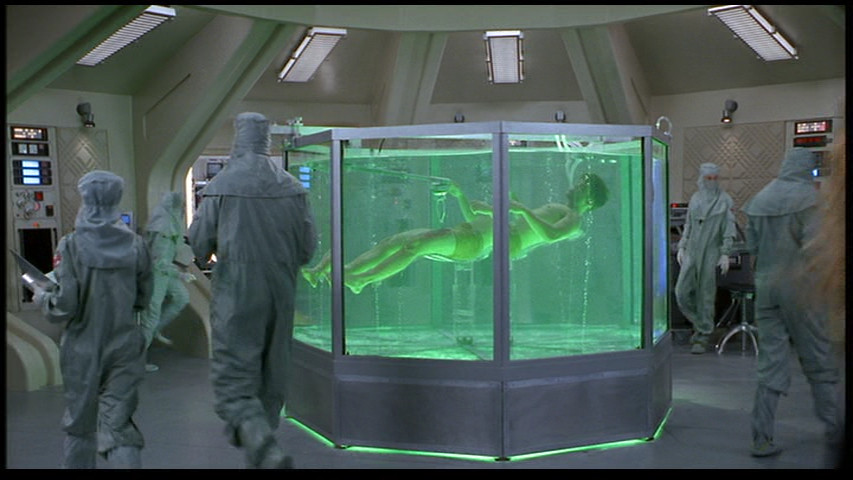 still from starship troopers (1997) johnny rico floating in a medical gel tank after being rescued from his encounter with an arachnid warrior unit. he is having the wound in his leg repaired, instead of letting his friends fuck it