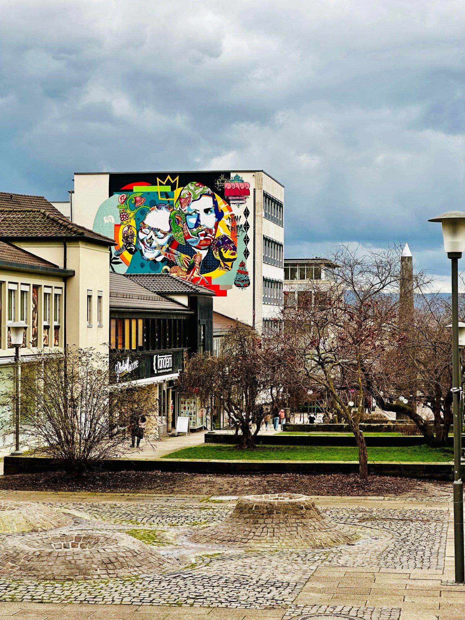 Zu sehen ist die Treppenstraße in Kassel mit Blick in Richtung Fridericianum. Auf der linken Seite der Häuser befindet sich ein wichtiger Bau mit bunter Wandmalerei.