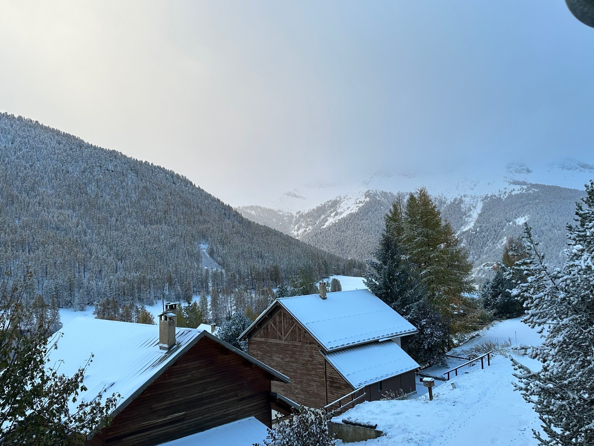 Une photo montrant au premier plan des chalets, en arrière-plan la montagne, tout est recouvert de neige.