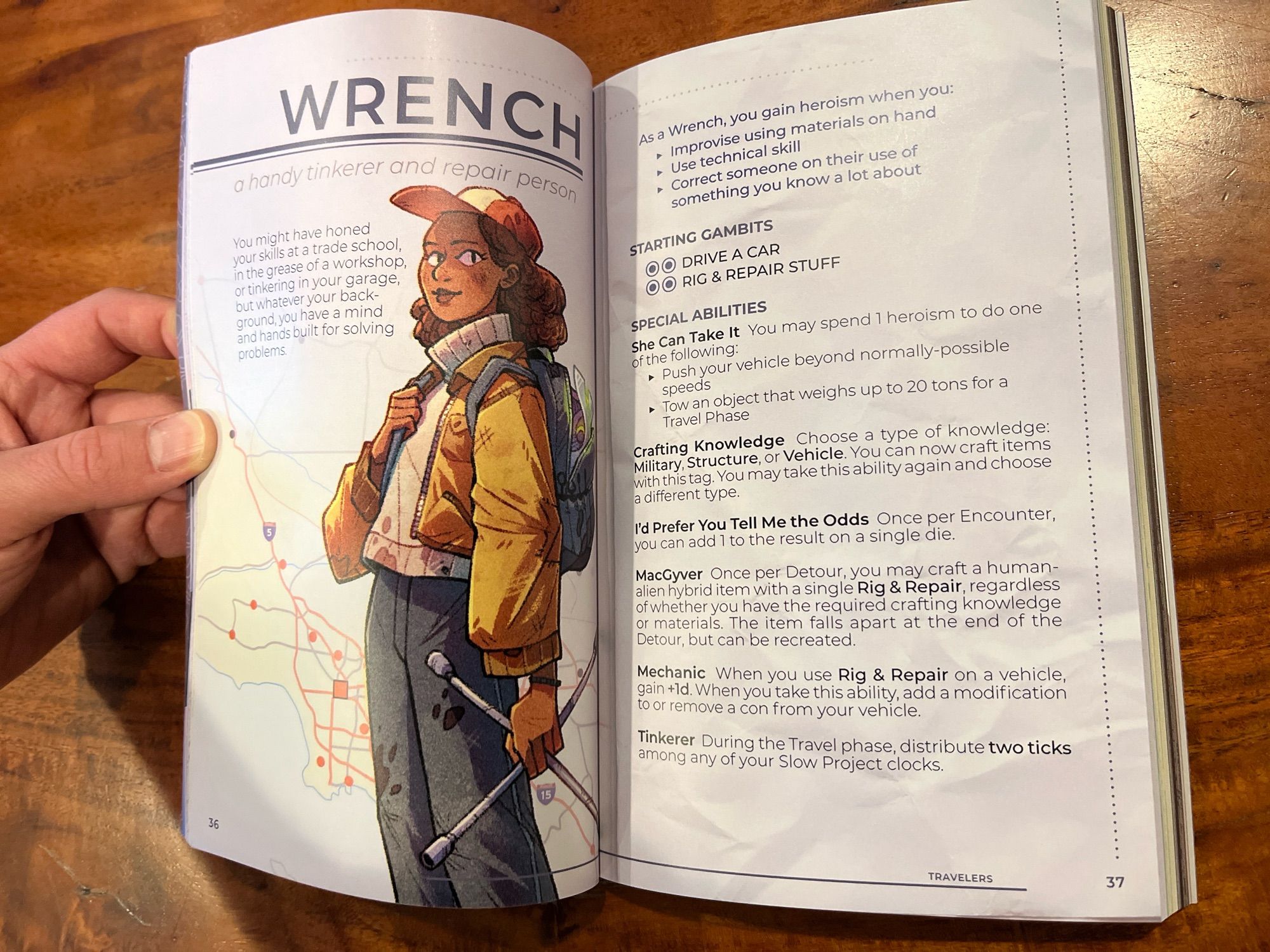 A hand opening the book to a page with the header “Wrench.” An image of a Black woman holding a lug wrench backed by a highway map. The facing page shows rules for the playing a Wrench in The Last Caravan.