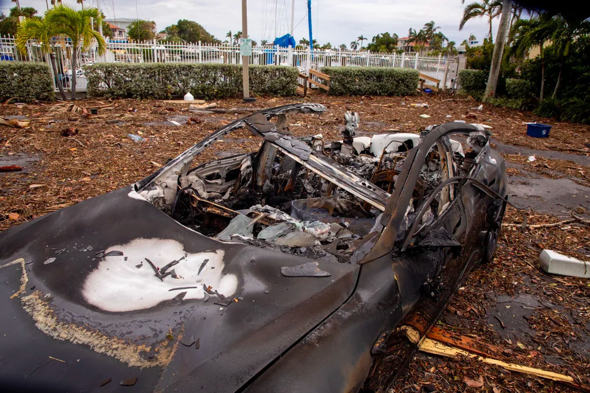 Photo of burned-out shell of a car amidst devastation, building wreckage.