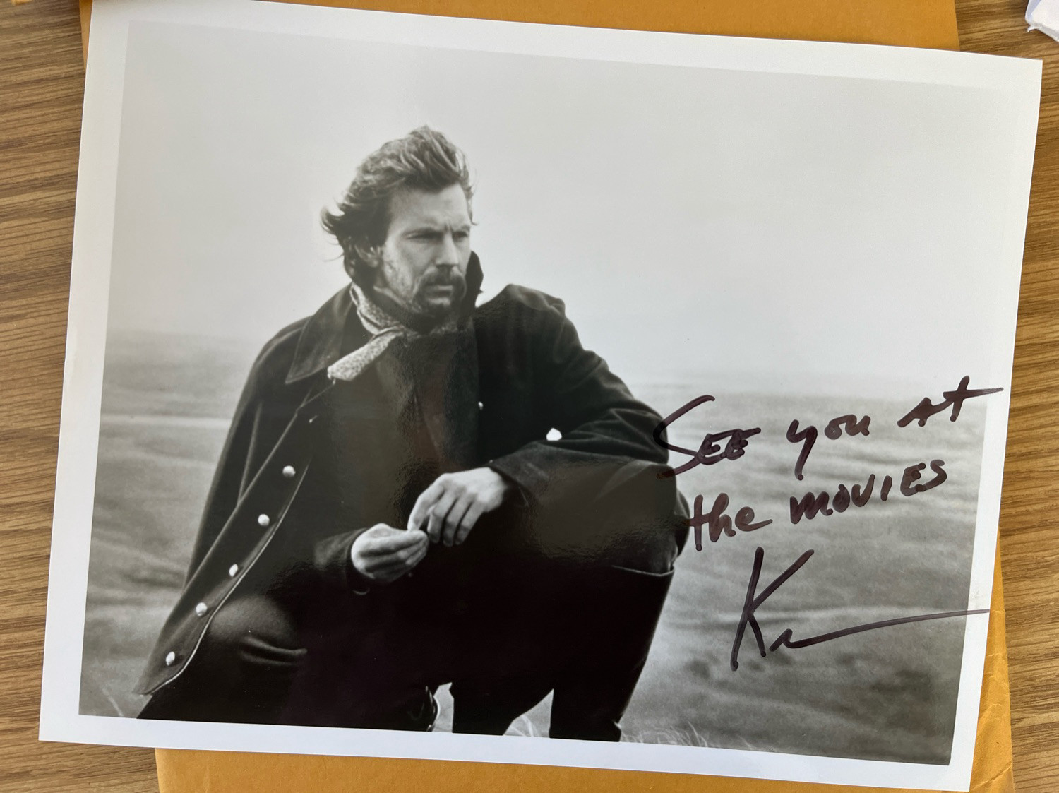 A black and white glossy photo of Kevin Costner from Dances with Wolves, autographed with the words “See you at the movies.”