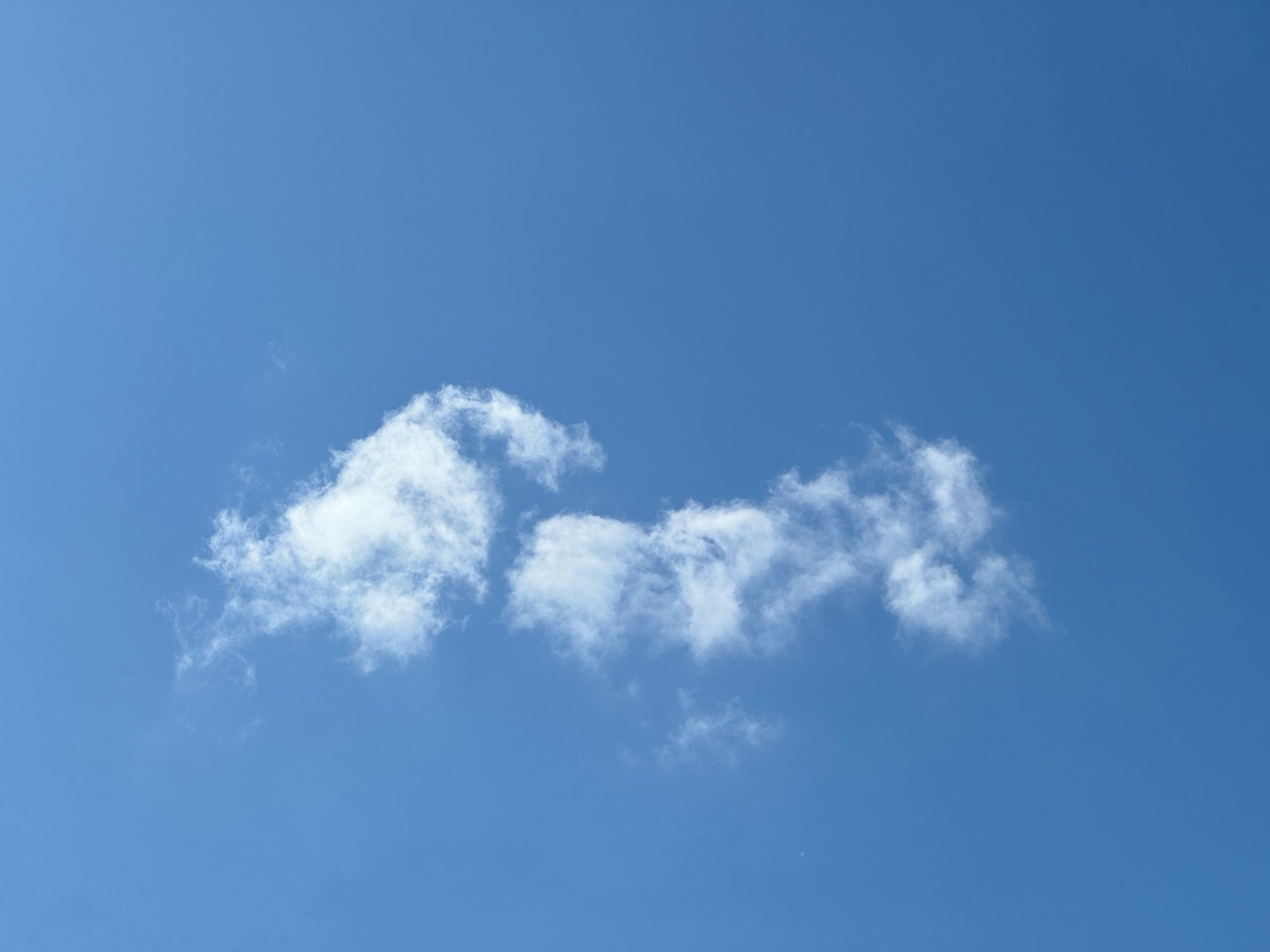 A small cloud against a blue sky on a sunny day.