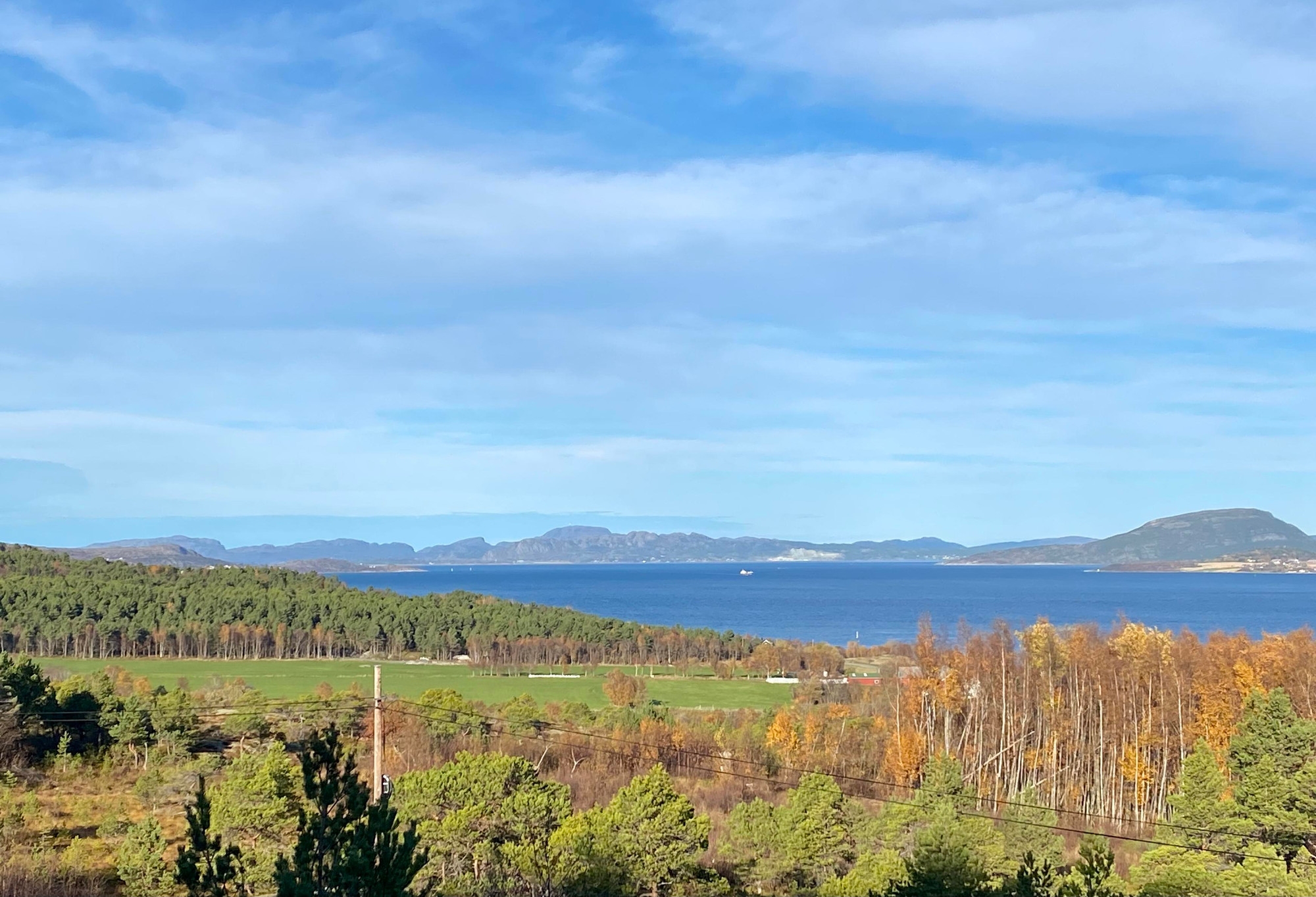 Utsikt over et høstfarvet landskap og Trondheimsfjorden i sol og lettskya vær. 