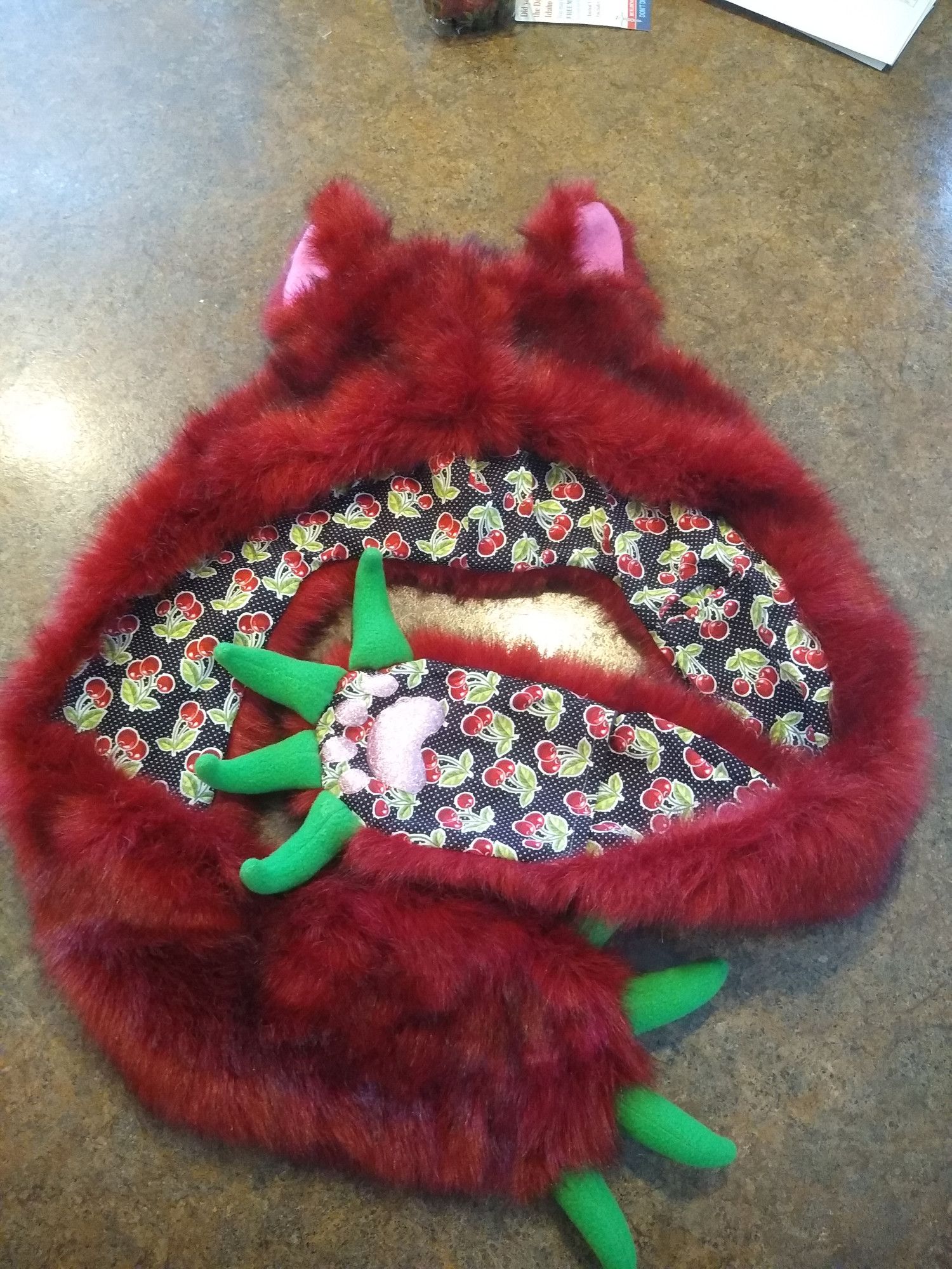 a red furred spirit hood with ears, green fleece claws, pink sparkly paw pads, and thick cotton lining with cherries printed all over