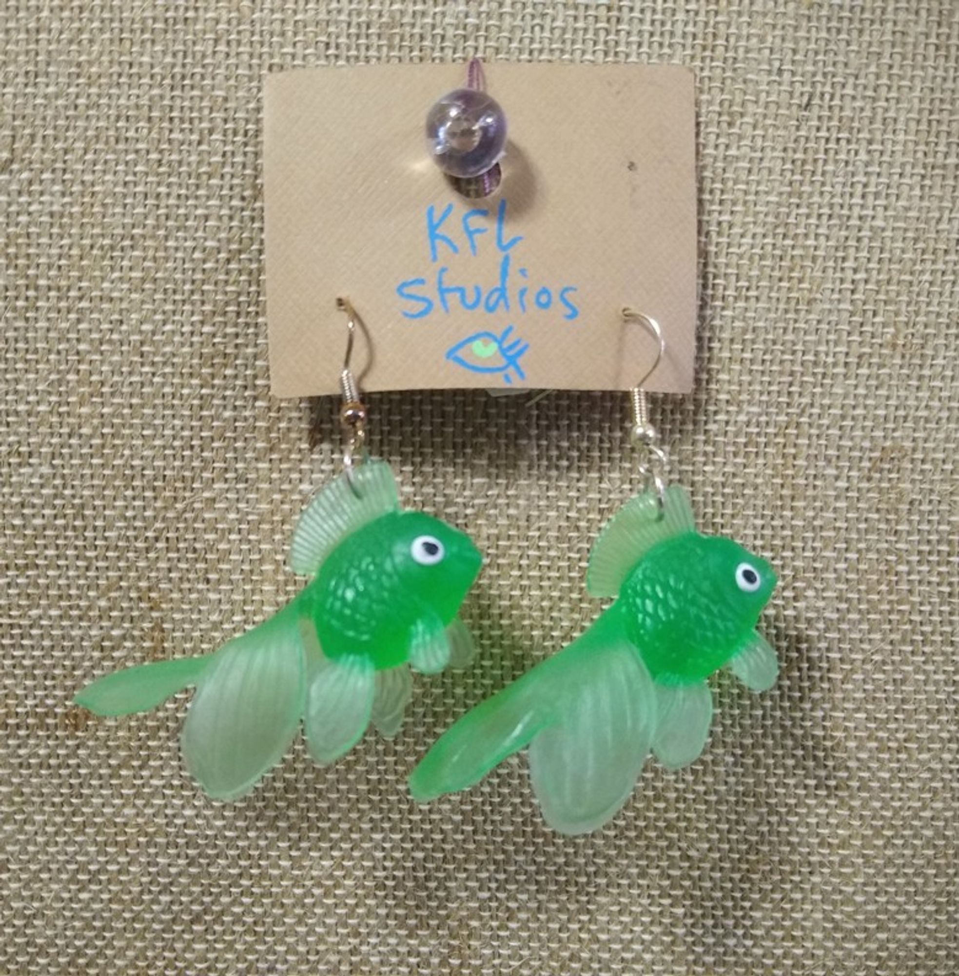 a pair of green goldfish earrings on fish hooks