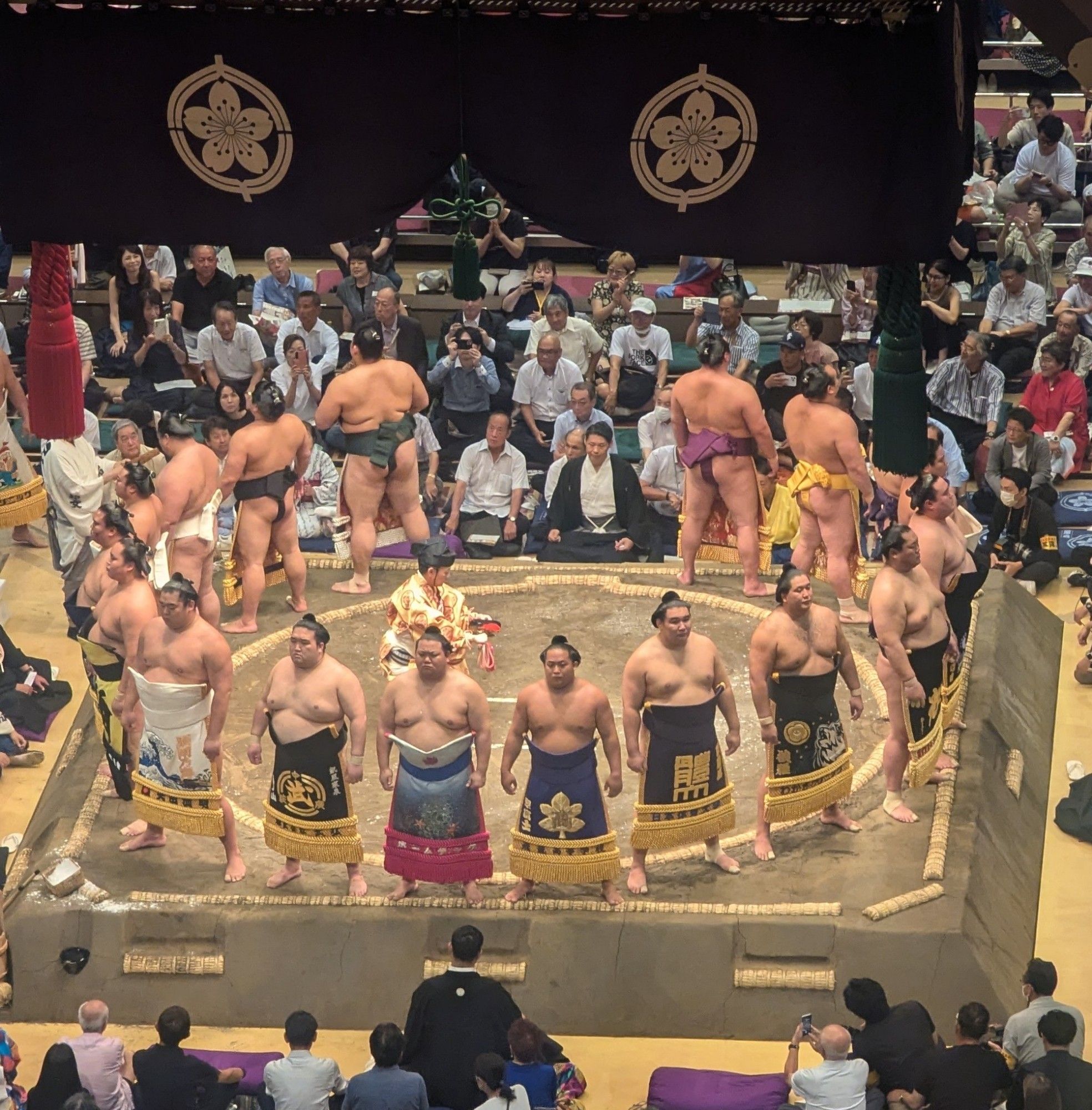 Sumo wrestlers standing around the ring in preparation for the next round.