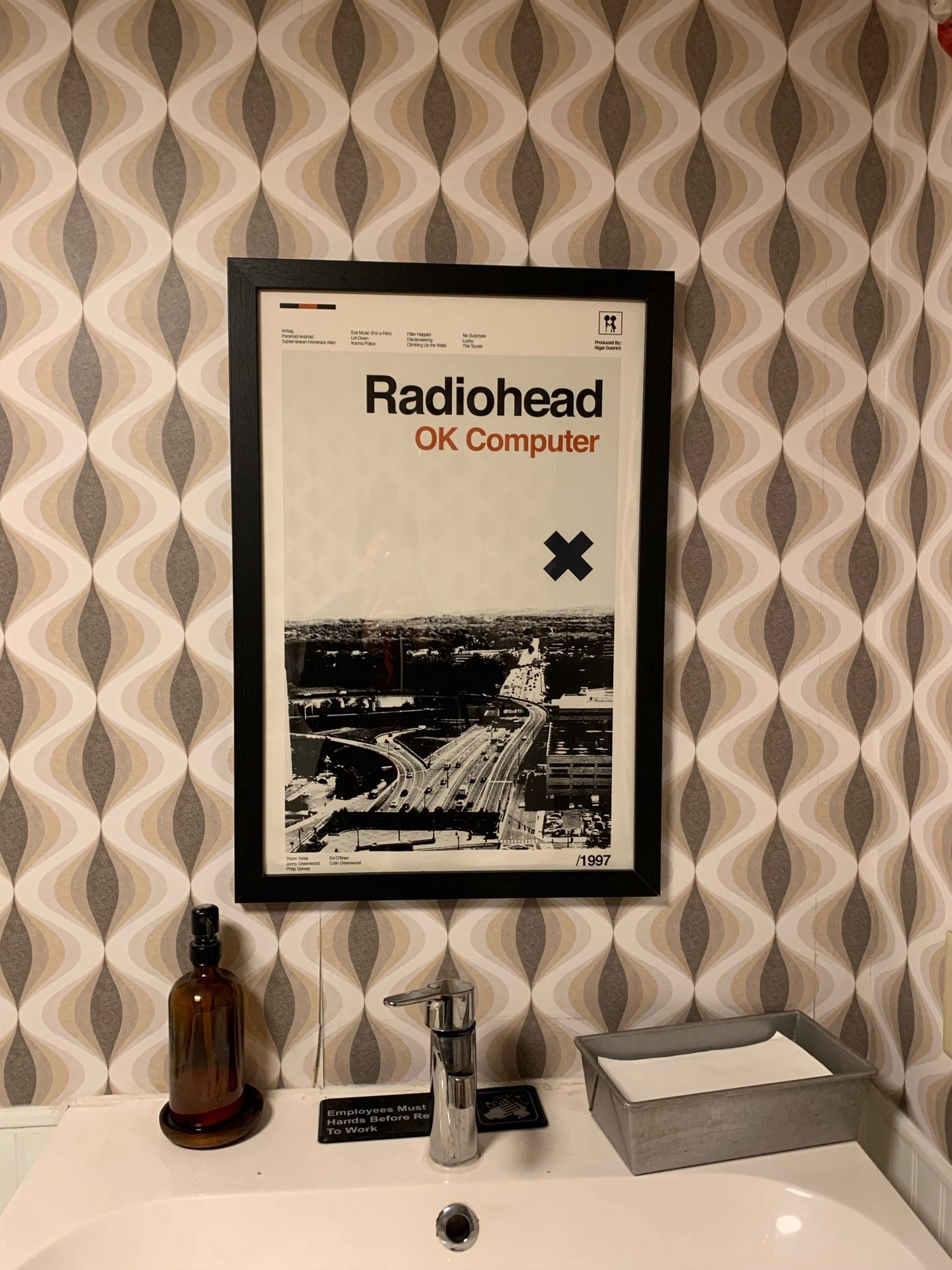 Radiohead OK Computer print hanging over a bathroom sink.