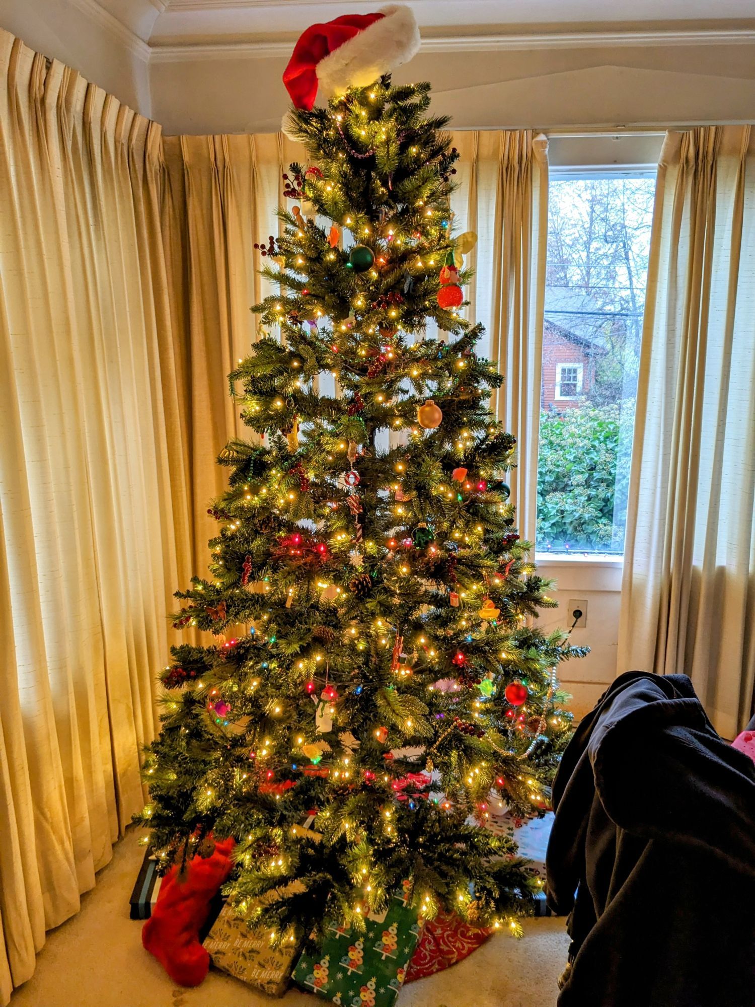 A fully lit and operational Christmas tree, topped with a Santa hat.