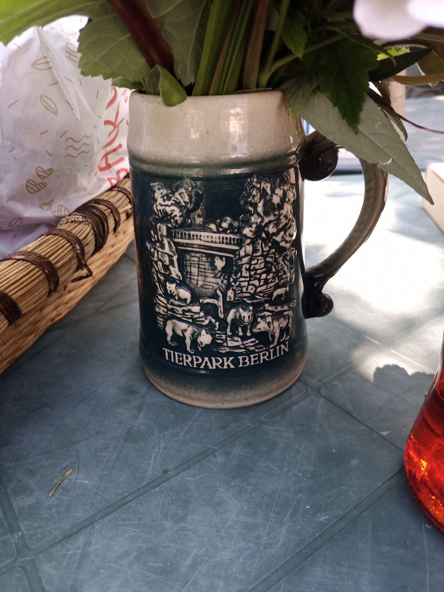 Ein Bierkrug mit Blumen darin.
Auf dem Krug finden sich verschiedenste Tiere vor einer Mauer, die Teile des Tierpark Berlin darstellt. Unter dem Bild steht Tierpark Berlin.