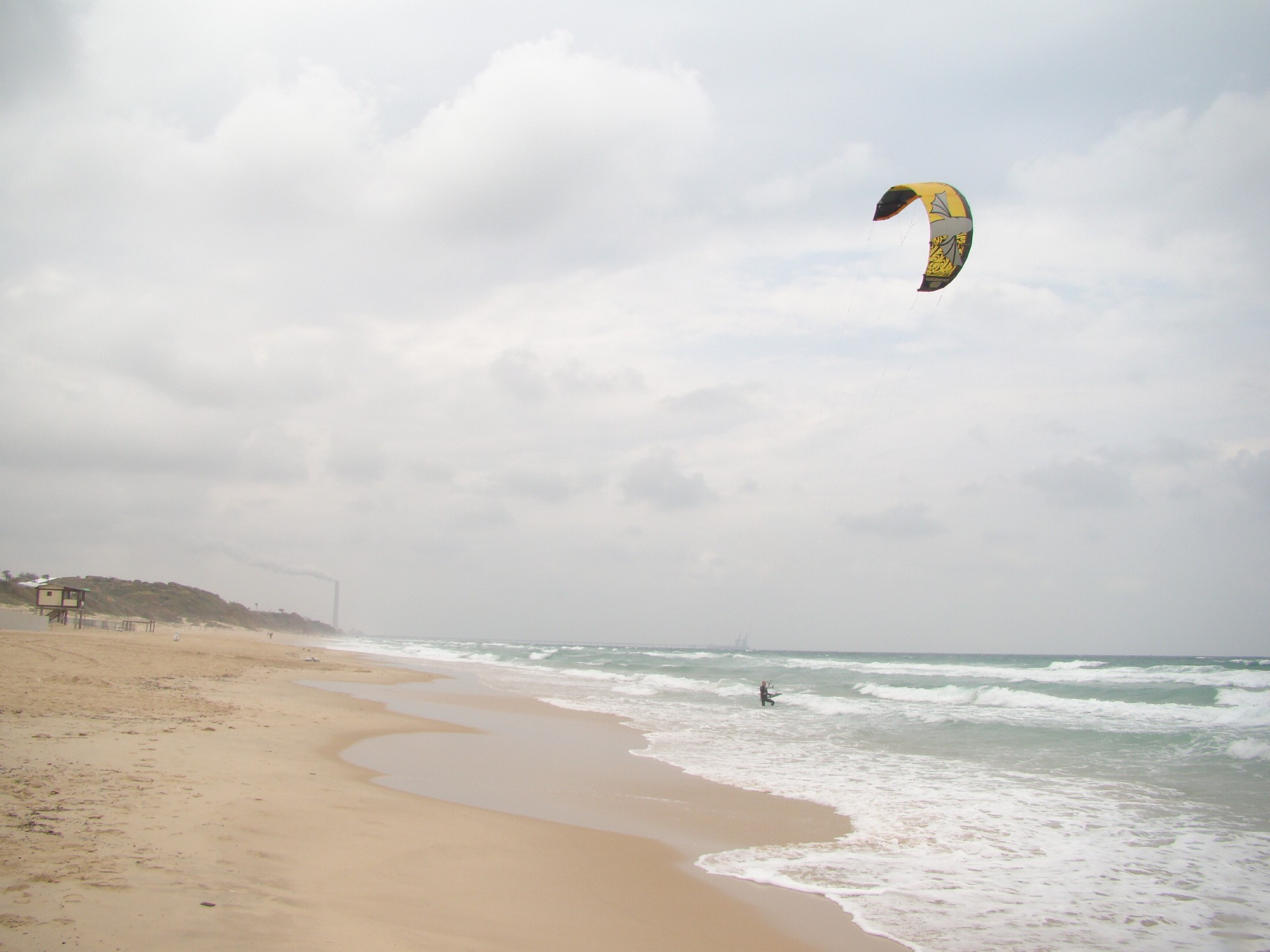 windsurfer on beach at al-majdal (ashkelon). the coal plant is visible in the distance