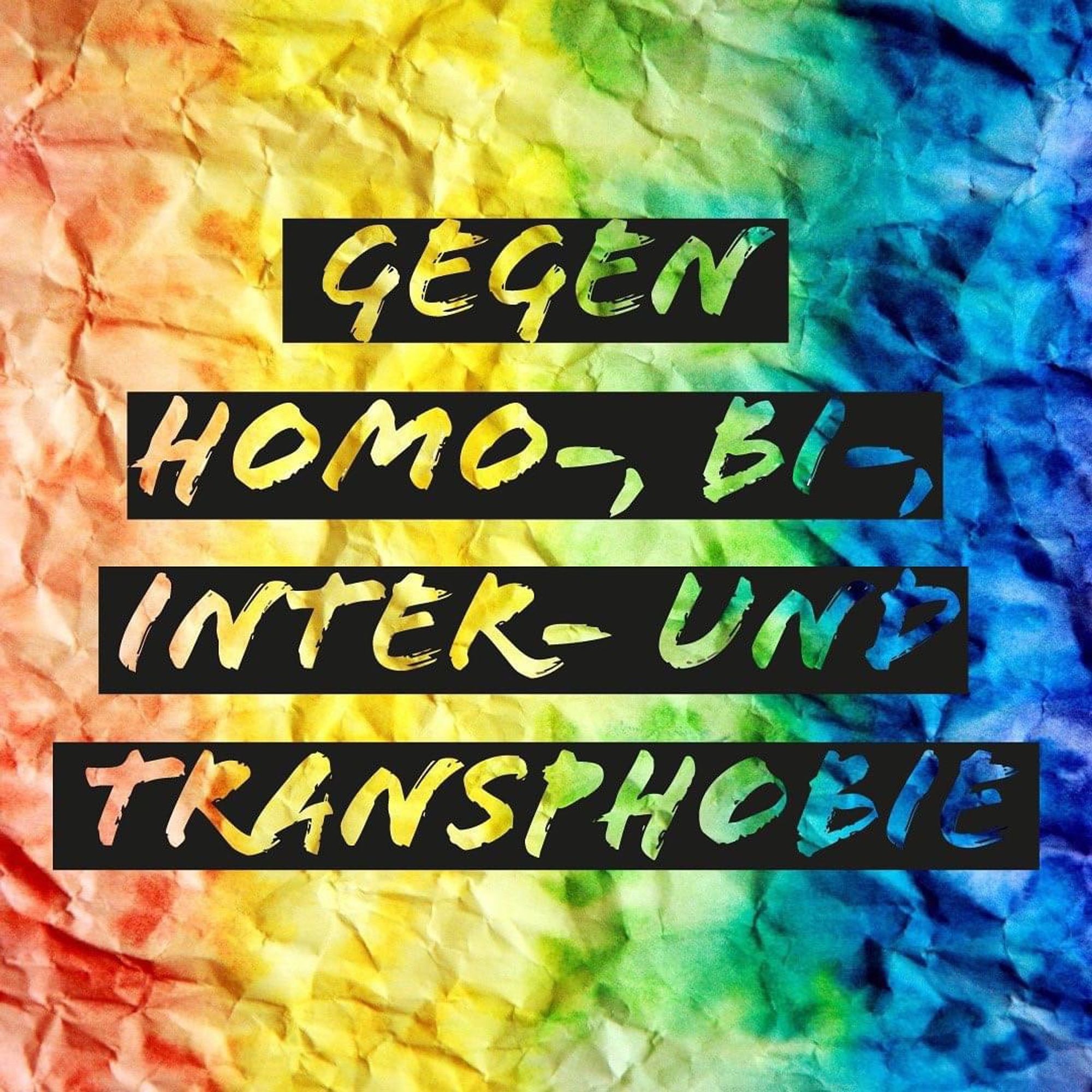 Auf einem Hintergrund in Regenbogenfarben steht geschrieben „gegen Homo-, Bi-, Inter- und Transphobie“.