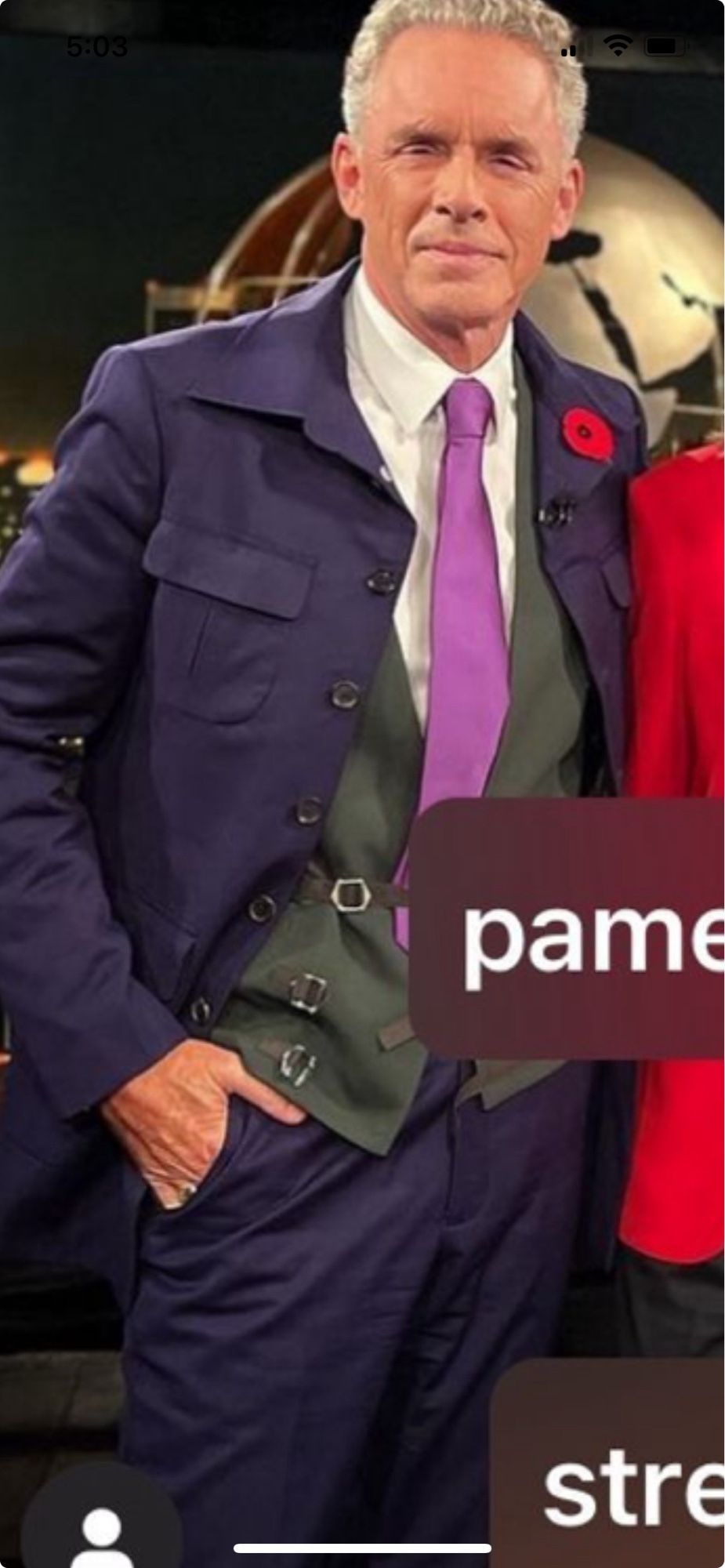 A closeup of Jordan Peterson wearing a purple jacket with far too many buttons and a great vest with multiple adjustment straps that are in the front for some reason.