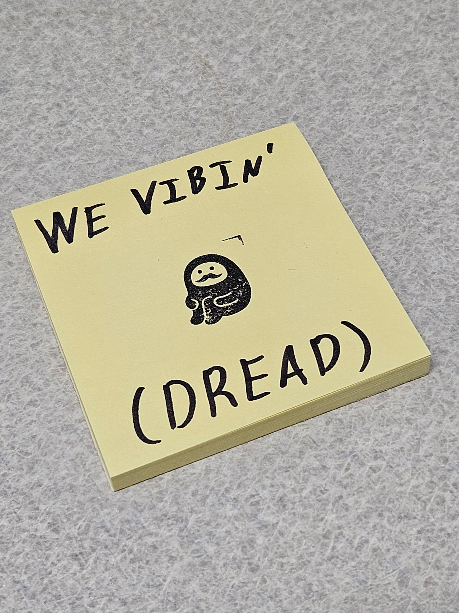 A pad of sticky notes with a simple mustached character in the center with surrounding text that reads "we vibin' (DREAD)"