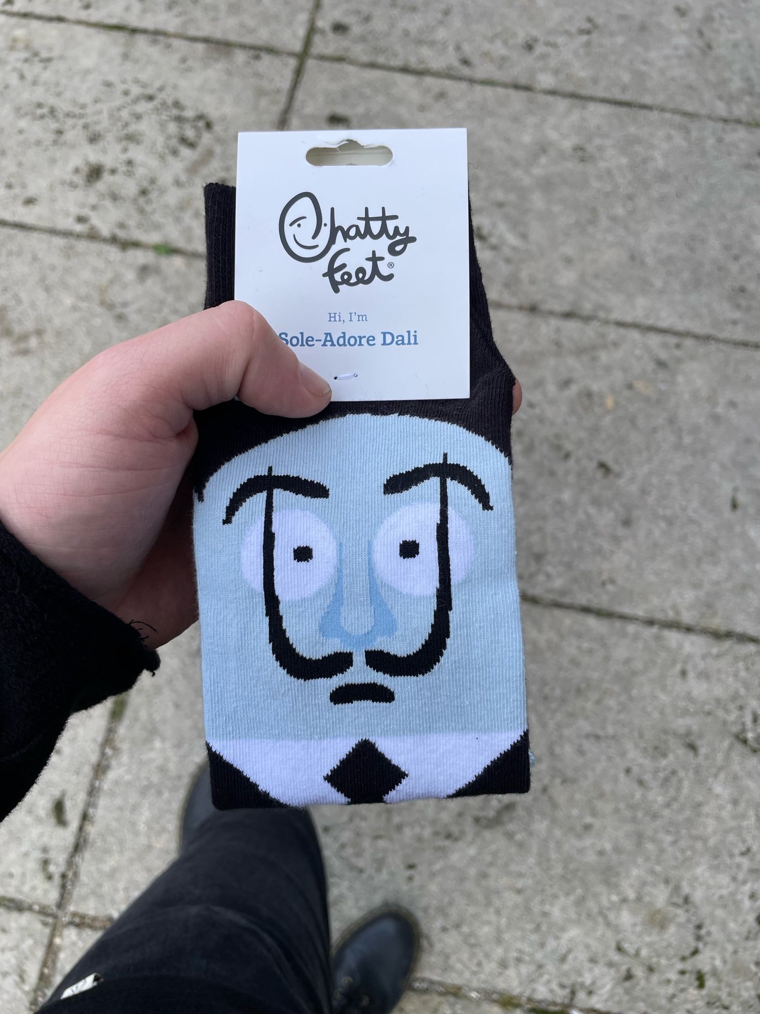 1 paar socken in meiner hand auf der eine comicversion von salvador dali abgebildet ist