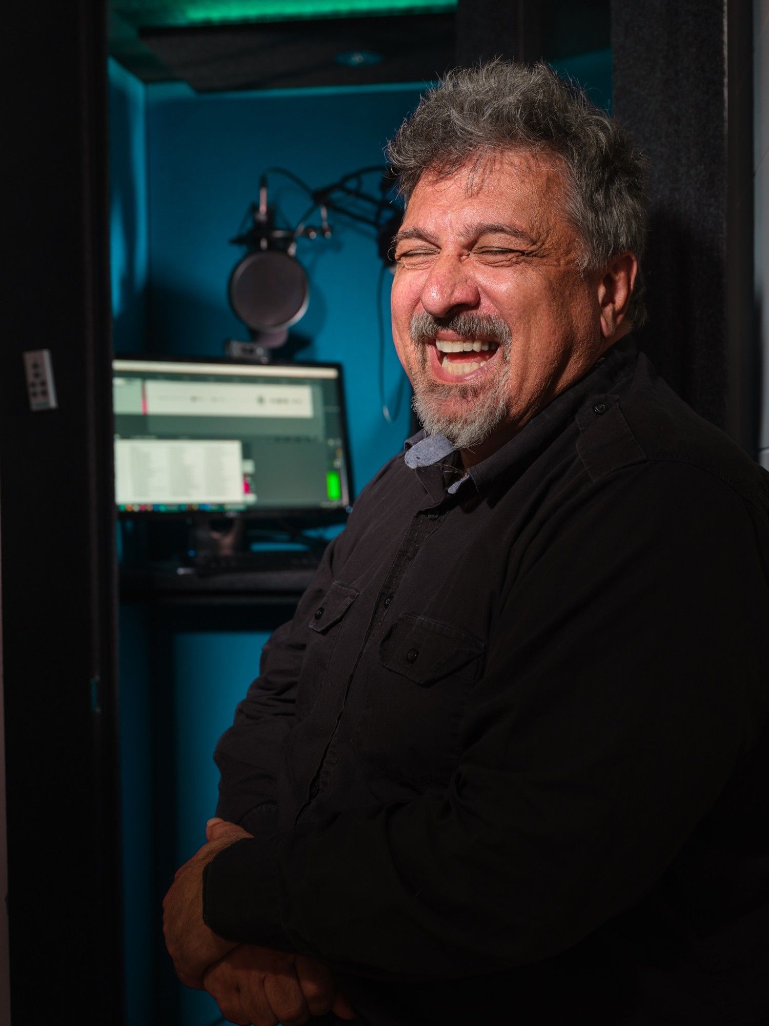 Karim standing and laughing in front of his recording booth