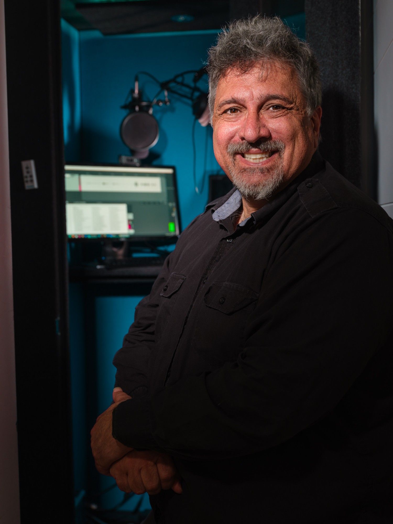 Karim standing with a broad smile in front of his recording booth